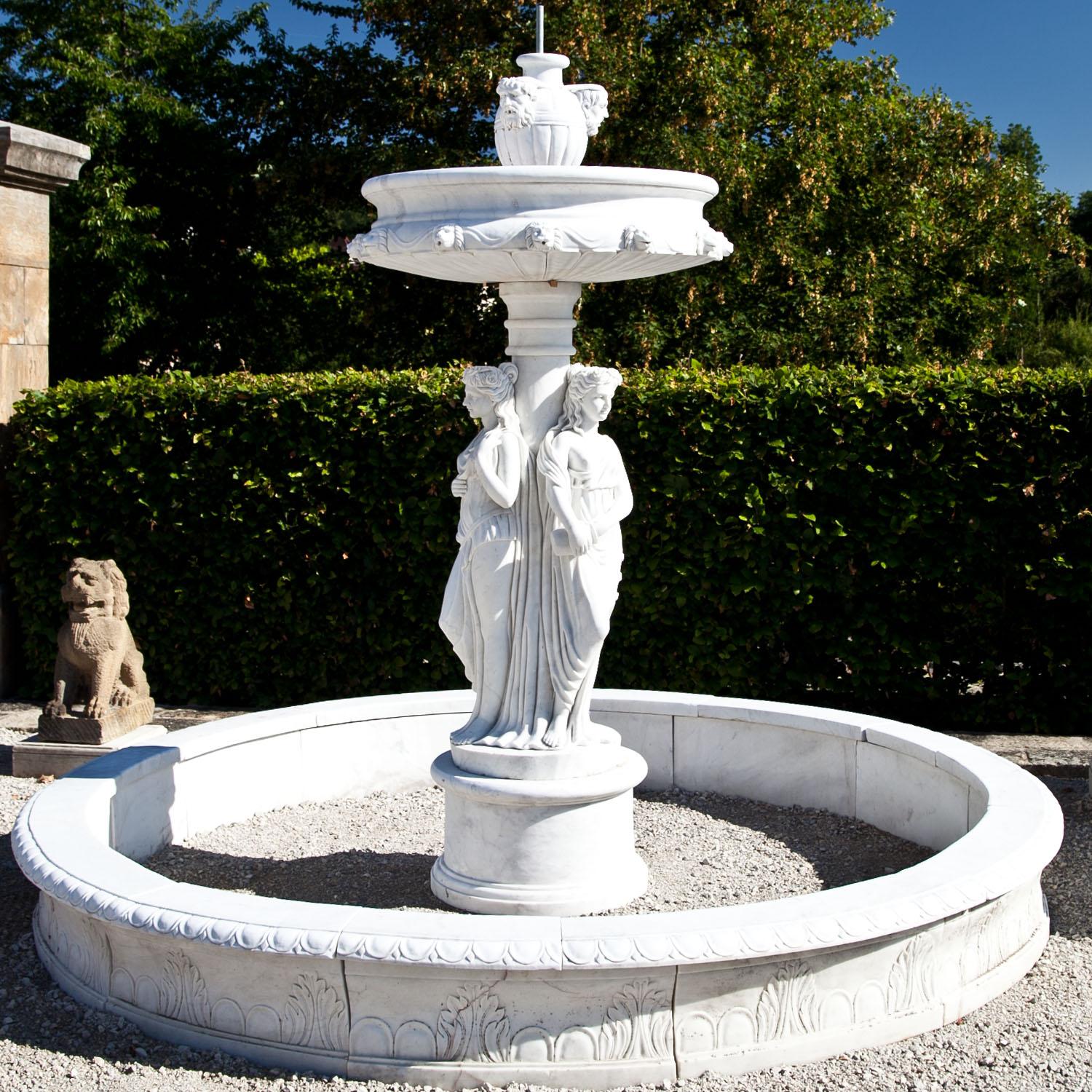 Large courtly fountain out of handcut and hand carved marble in a neoclassical style. The three graces surround the central column, above is another basin with waterspouts in the shape of lion and male head's.
The wall of the large basin is H 36 x