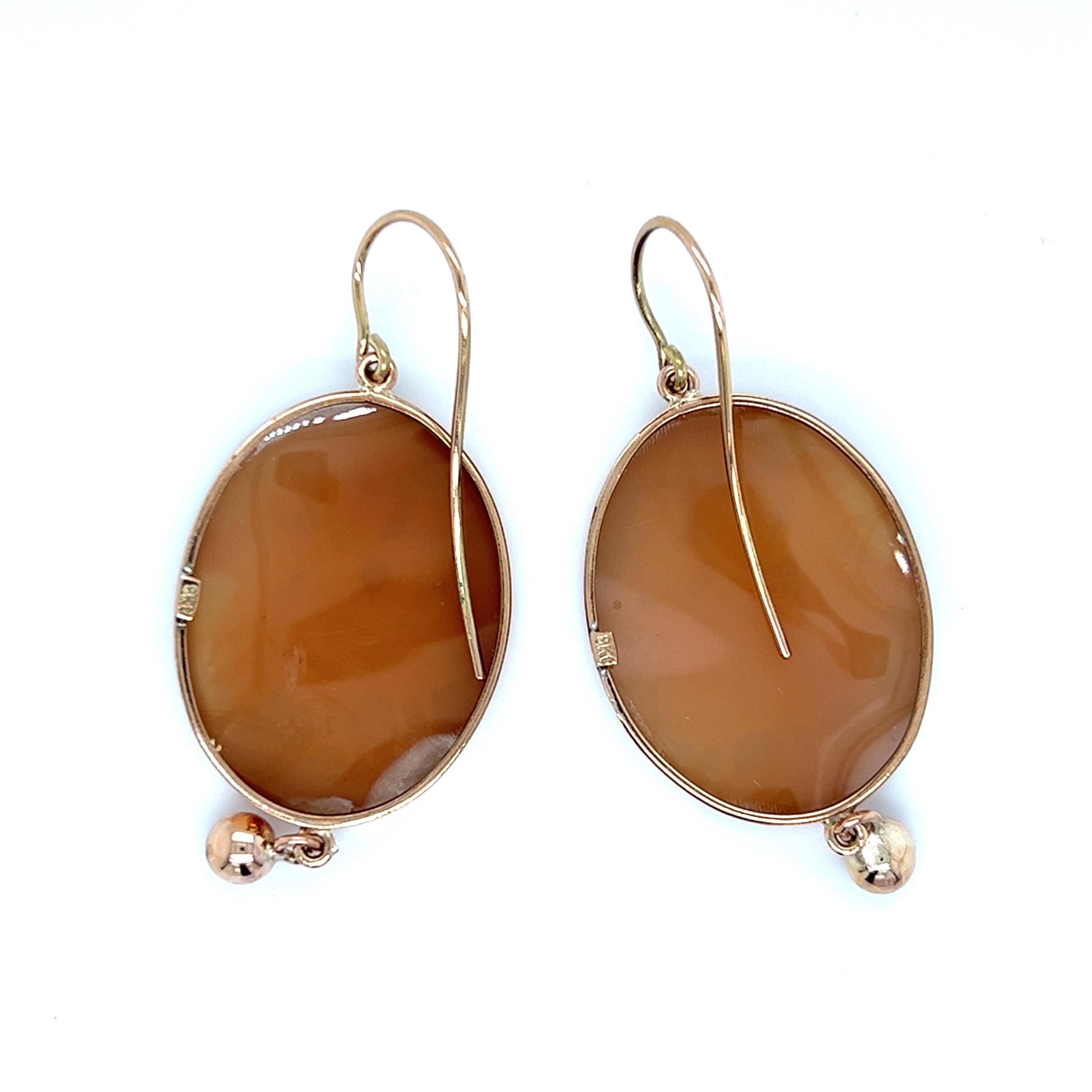 One pair of 9-karat rose gold shell cameo earrings featuring The Three Graces design.  The earrings measure just over two inches long, and one inch wide, and are complete with traditional hook closures.