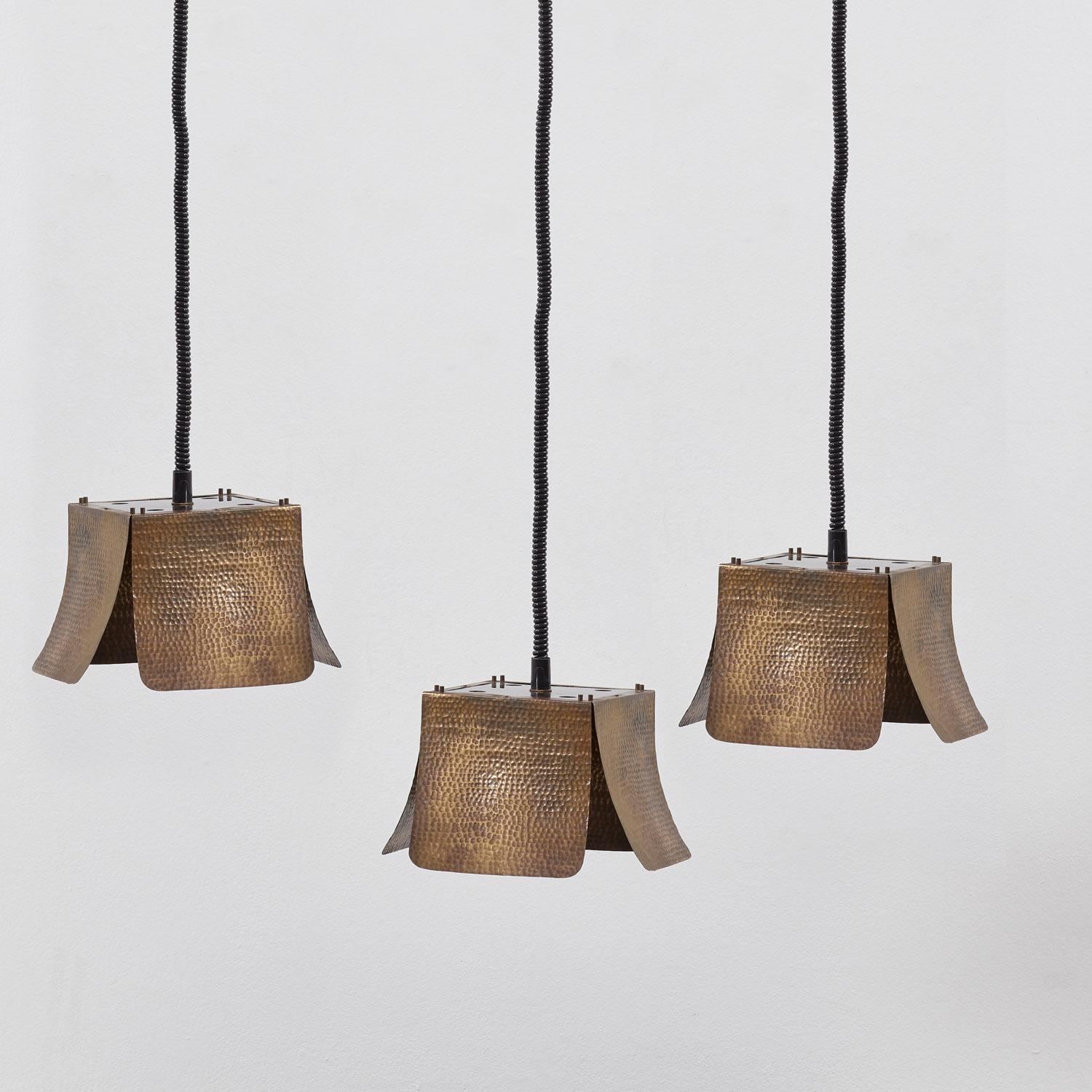 A set of three 1970s ceiling lamps, attributed to the Florentine designer Tommaso Barbi (b.1944-2015), known for his expressive use of brass. 

Each lamp is characterised by four hammered brass panels, articulated with a rational, brutalist