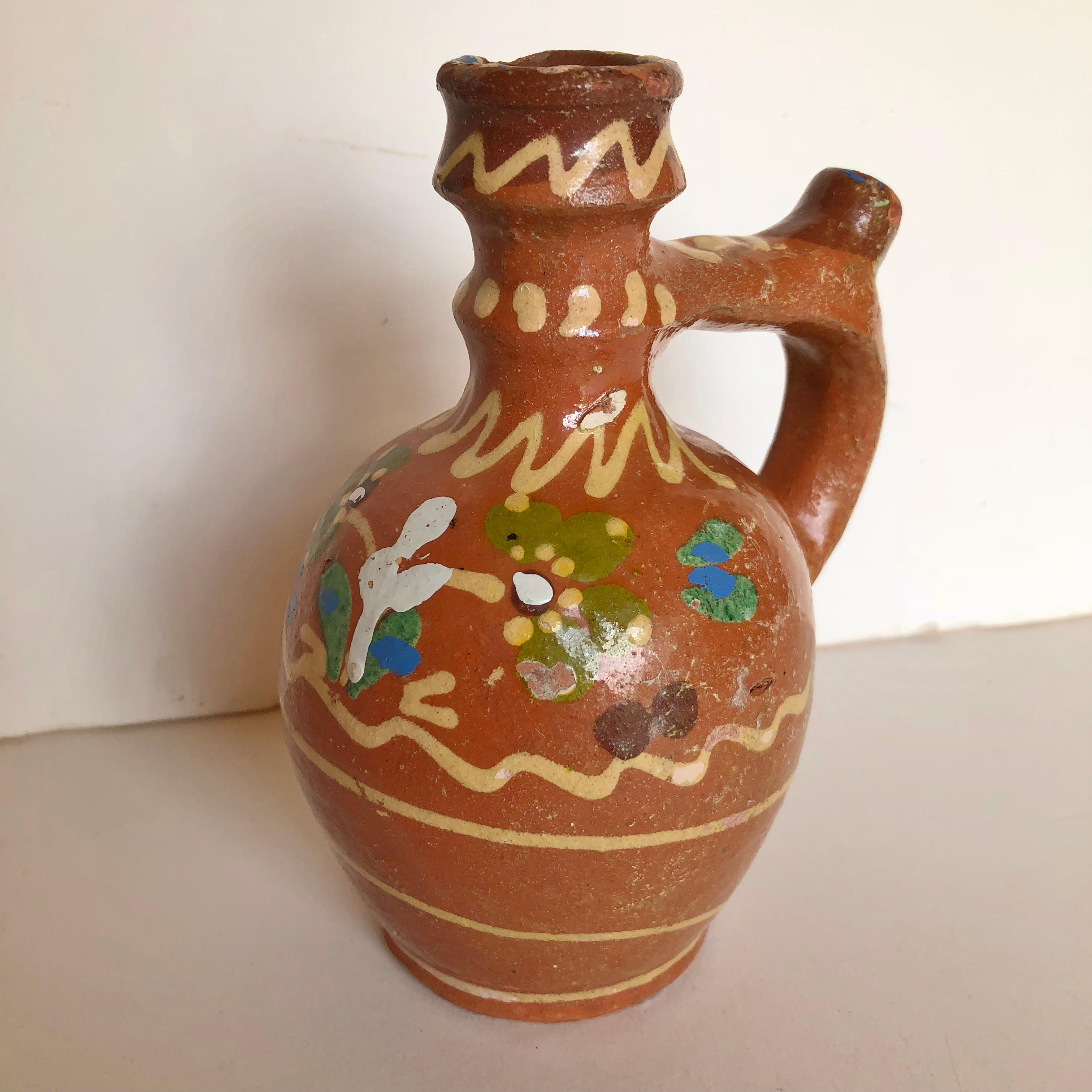 Three handmade pottery folk art carafes, jugs from Transylvania, Serbia.  They have a platter painted glaze and were used for water or wine. There are minor chips and paint loss but are wonderful period pieces of folk art. The larger one is 8
