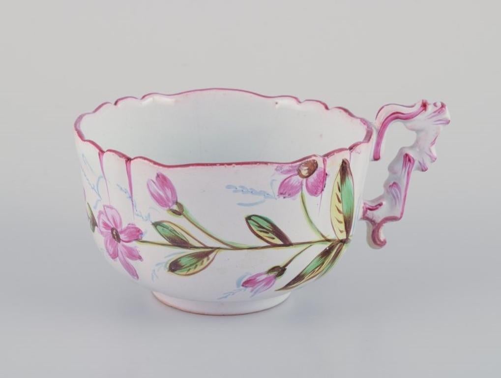 Hand-Painted Three hand-painted tea cups and saucers in faience with motifs of flowers. For Sale