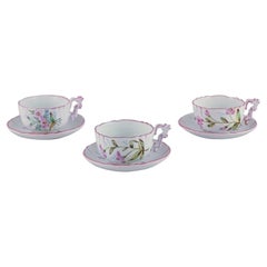 Tre tazze da tè e piattini in maiolica dipinti a mano con motivi di fiori.