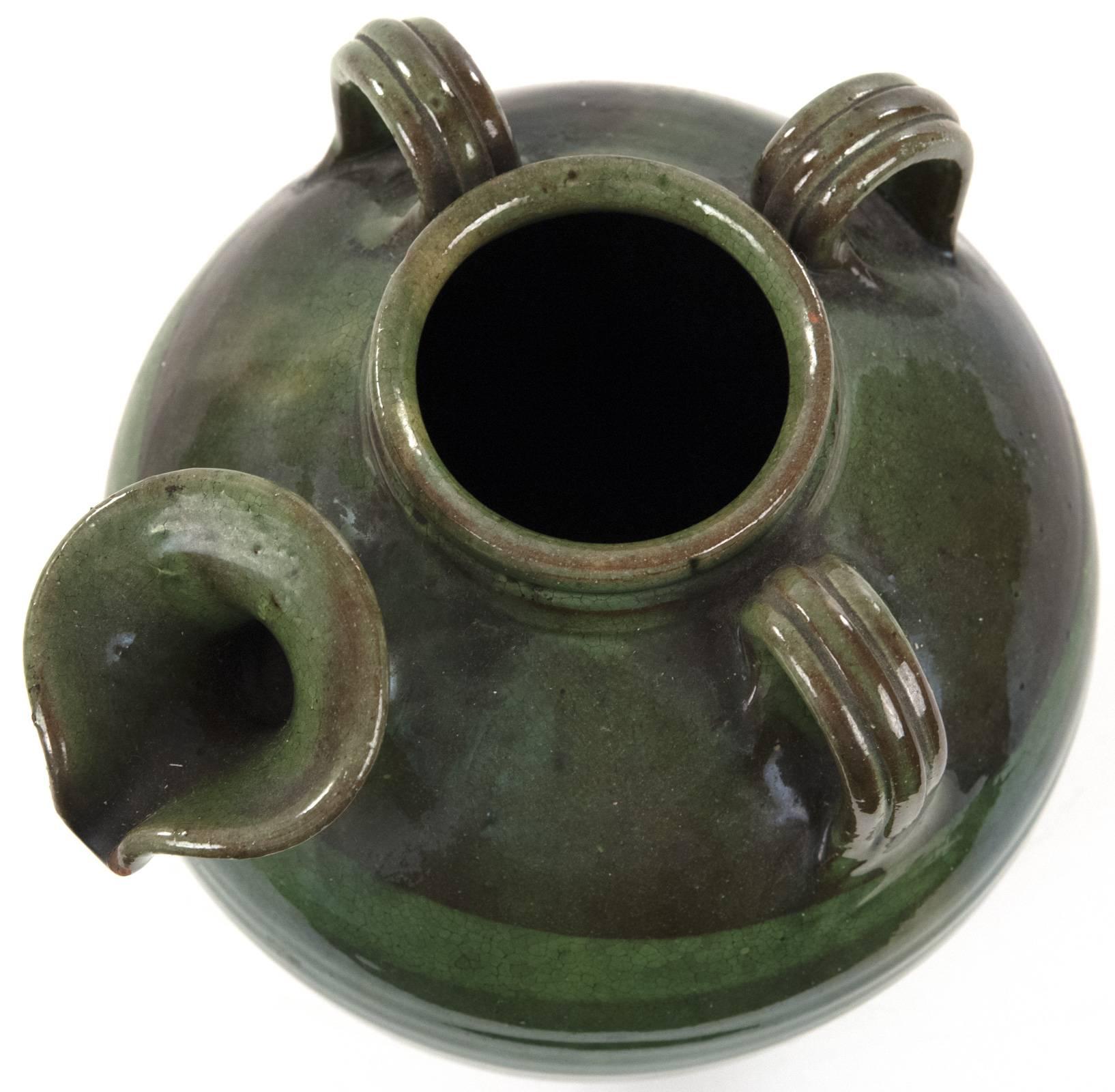 A green glazed jug of baluster form with three incised handles affixed from neck to shoulder, with a shaped pinched spout. Measures: 9 ¾ x 8 inches.