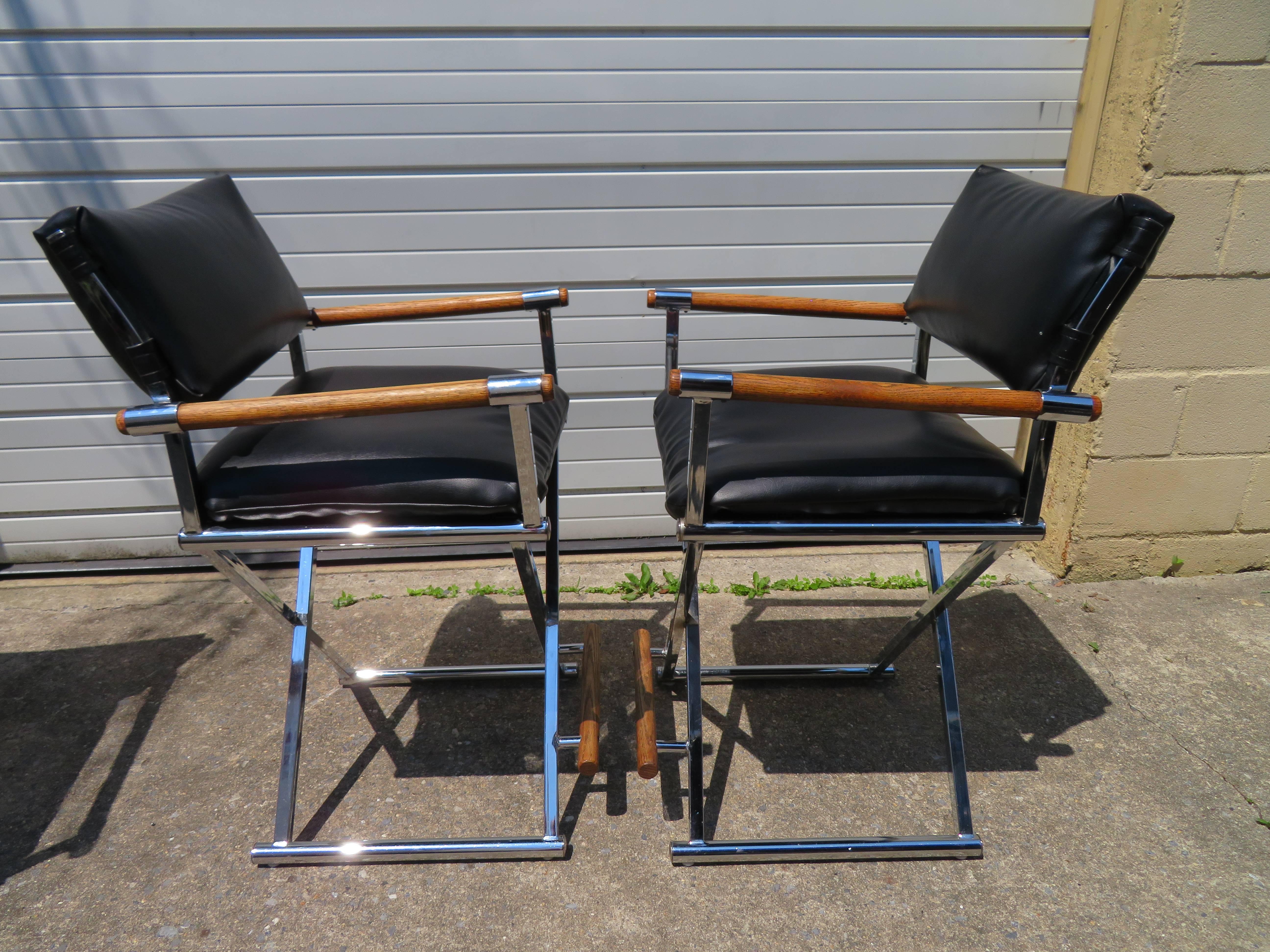 A vintage set of three director's chair bar stools in black faux leather with chrome X-base frames and wooden arm rests attributed to Milo Baughman. The seat height on these is 26.5