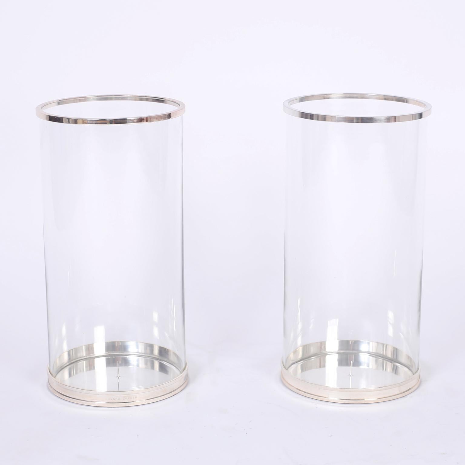Here are three chic hurricane candleholders each with silvered metal bases and rims, glass cylinders, and a sleek modern form. Outside pair are signed Ralph Lauren on the bases.

Measures: Outside pair- Height 18, diameter 9
Center single- Height