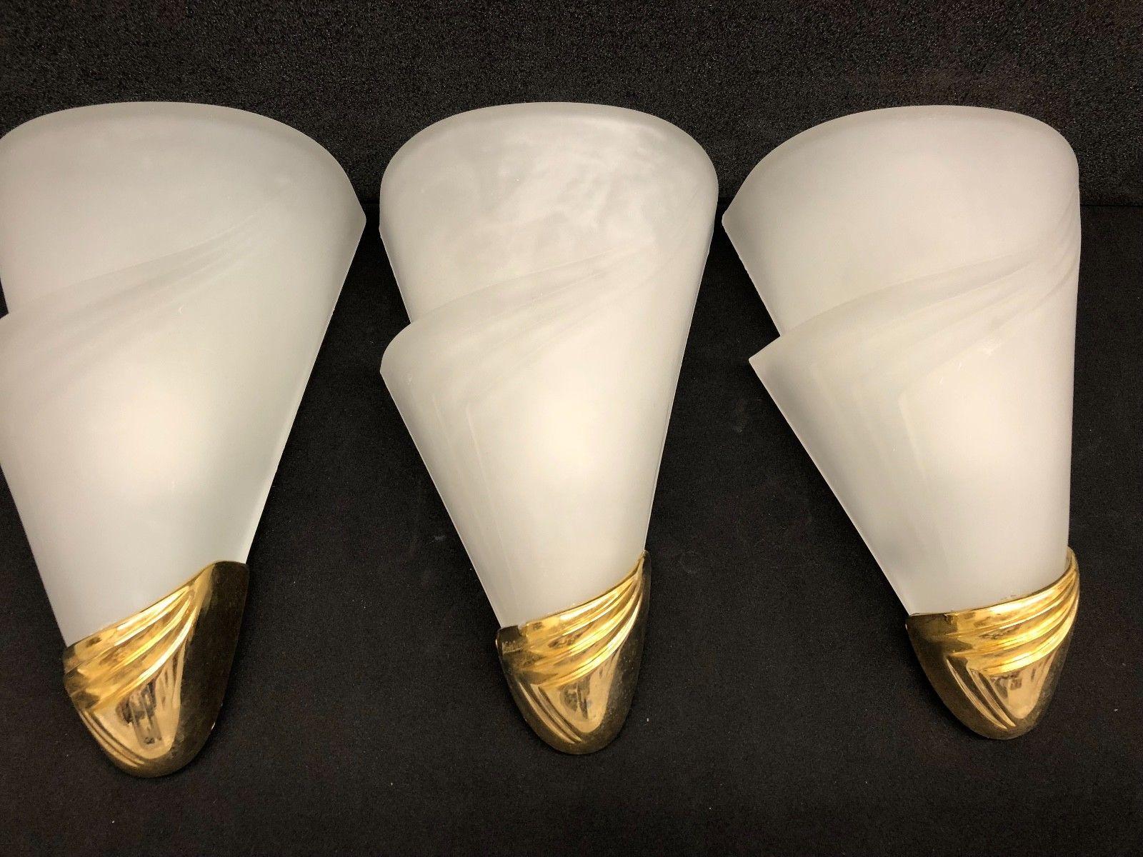 Three beautiful sconces in the style of Art Deco, circa 1960s, in excellent original condition, composed of an elegant gold brass frame, and with one light. The sconces are 10 1/2