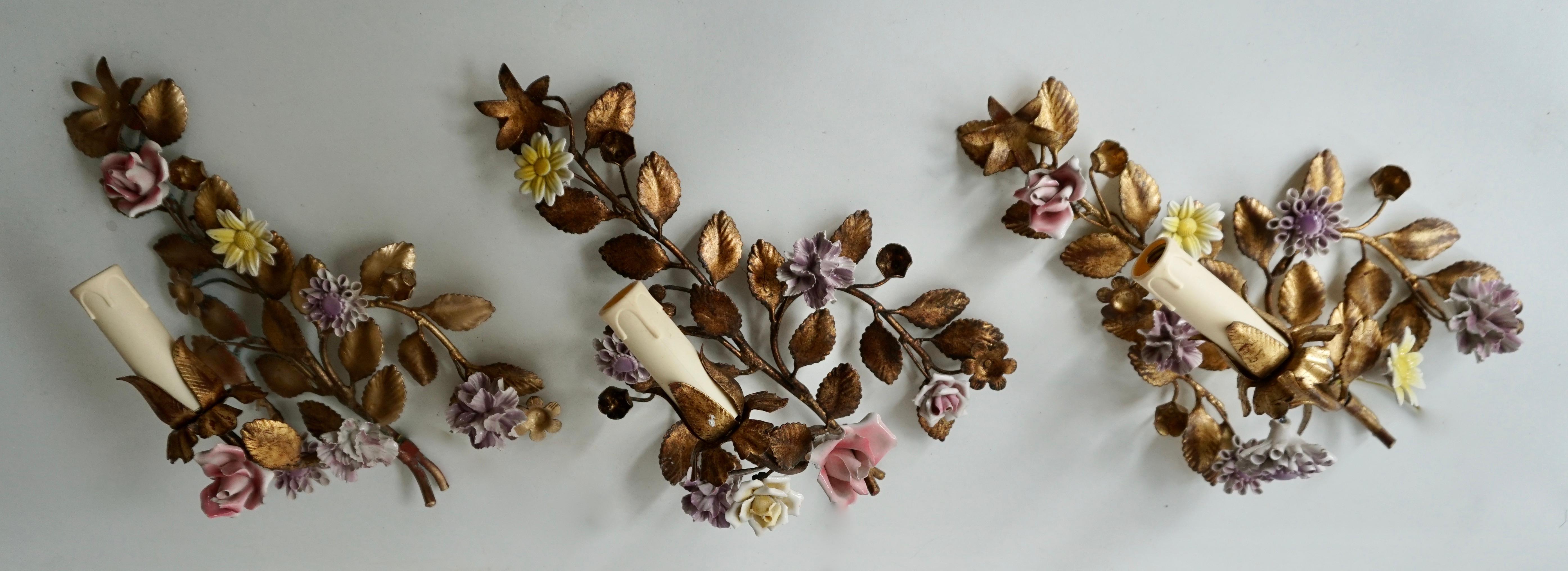 Decorate a powder room or an entry with these elegant antique wall lights, crafted in Italy, circa 1950, each metal sconce features one arm and is embellished by colorful hand painted porcelain flowers and gilt metal branches and leaves. The