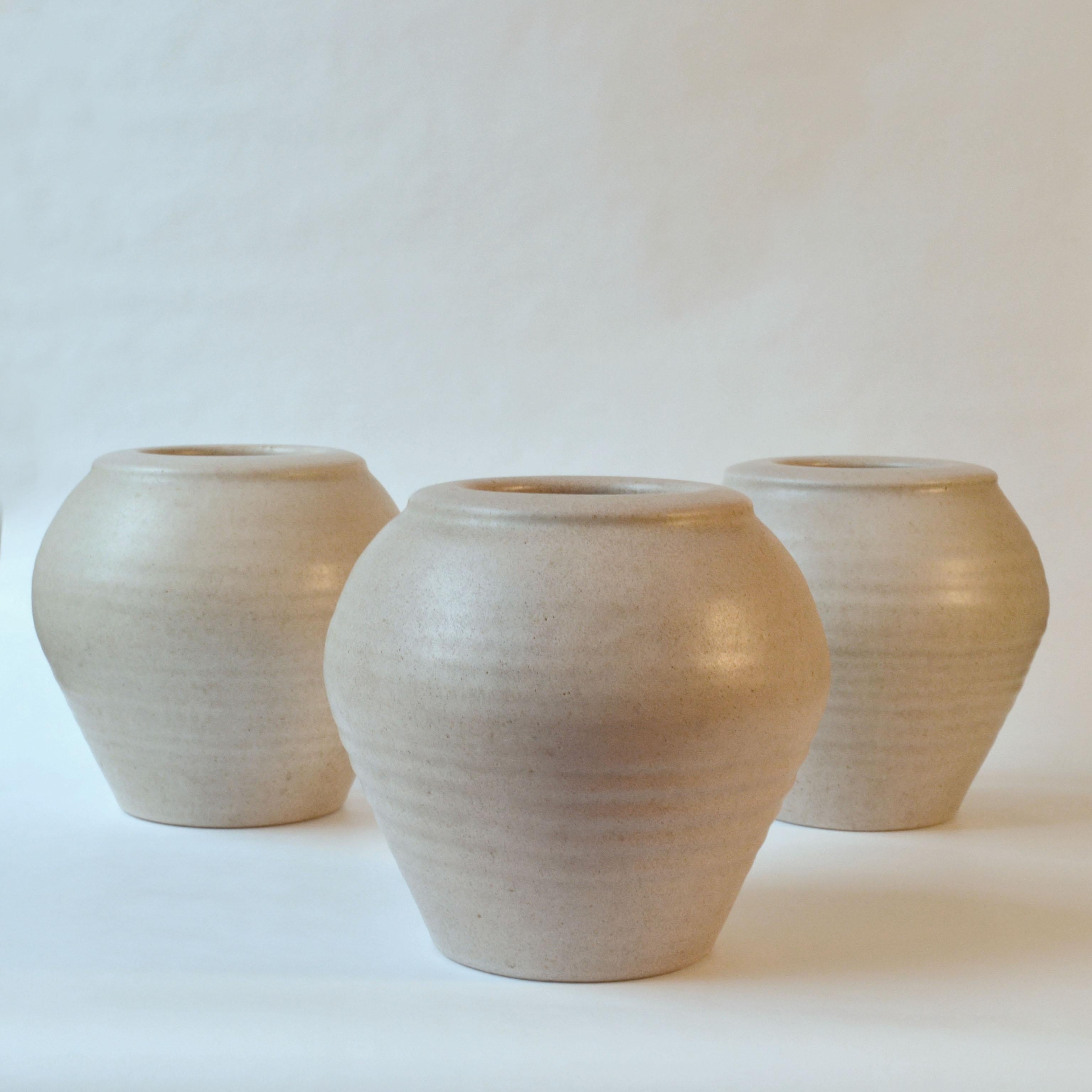 Set of studio pottery vases turned by hand on the wheel into a urn shape with protruding lip border. They are crafted by a Dutch ceramist who required both art and skill in the 1980's. The warm ivory white glazes has tiny specks of darker tones