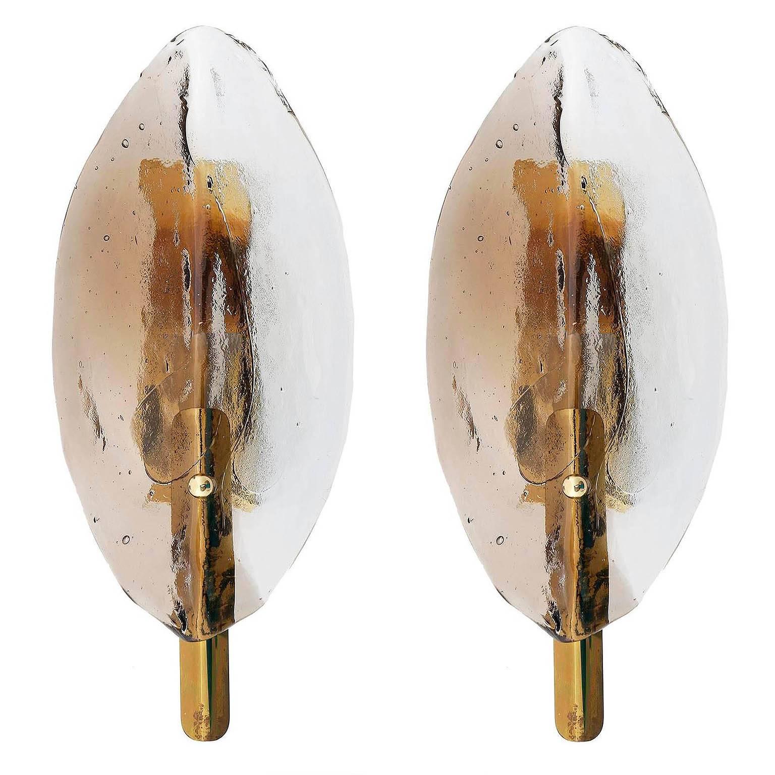 Three beautiful J.T. Kalmar wall lights, manufactured in midcentury, circa 1970 (end of 1960s and beginning of 1970s).
A leaf-shaped two-tone (clear and smoked or amber) Murano glass with a brass fixture.
Excellent condition with little patina to