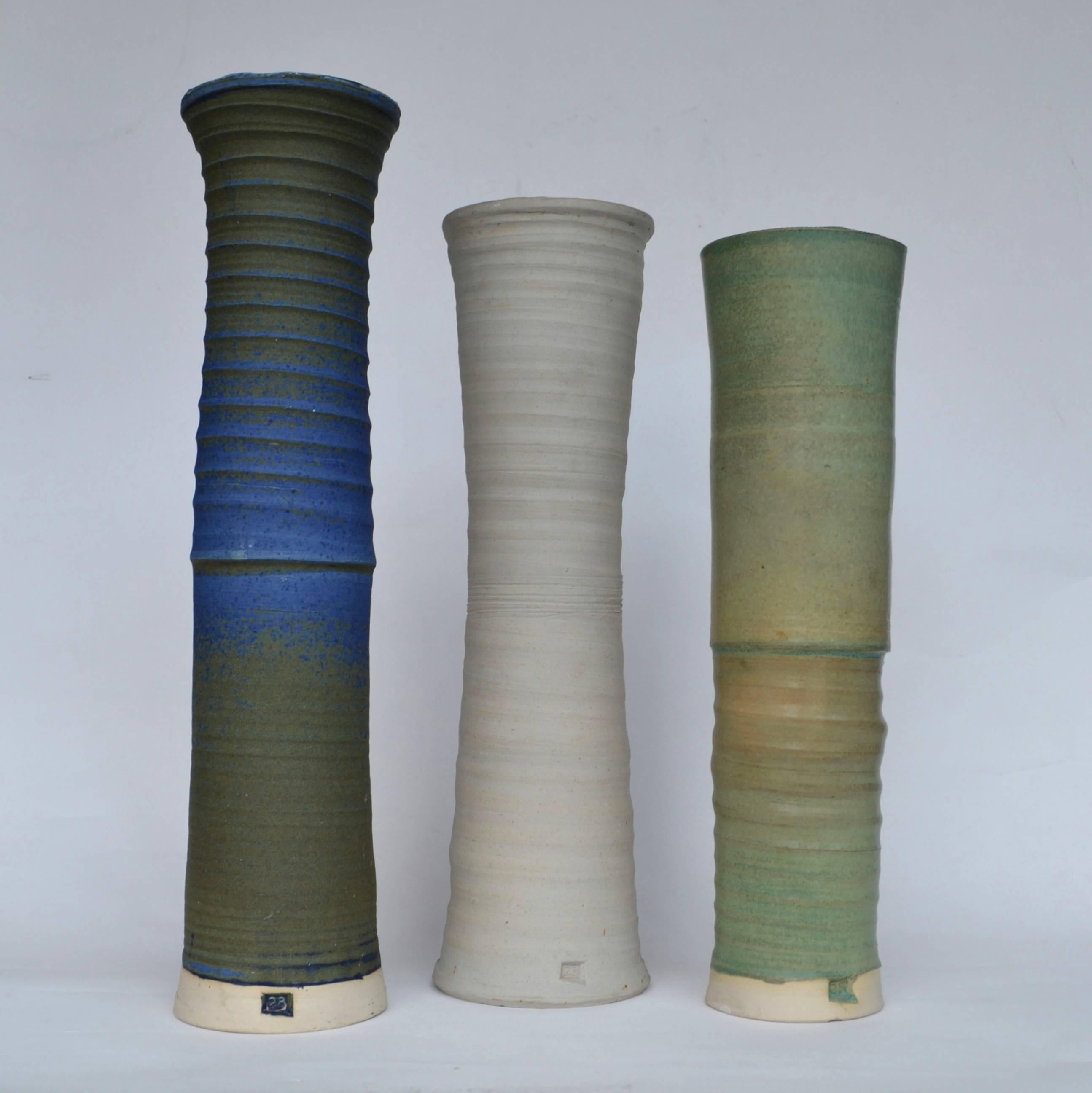 Elongated vases or vessels in muted tones of blue, green and sand color by the UK ceramist Virginia Rood Pane.
They have slightly different heights (49, 44, 42 cm) and shapes and the textures show the hand movement of the throwing process of each