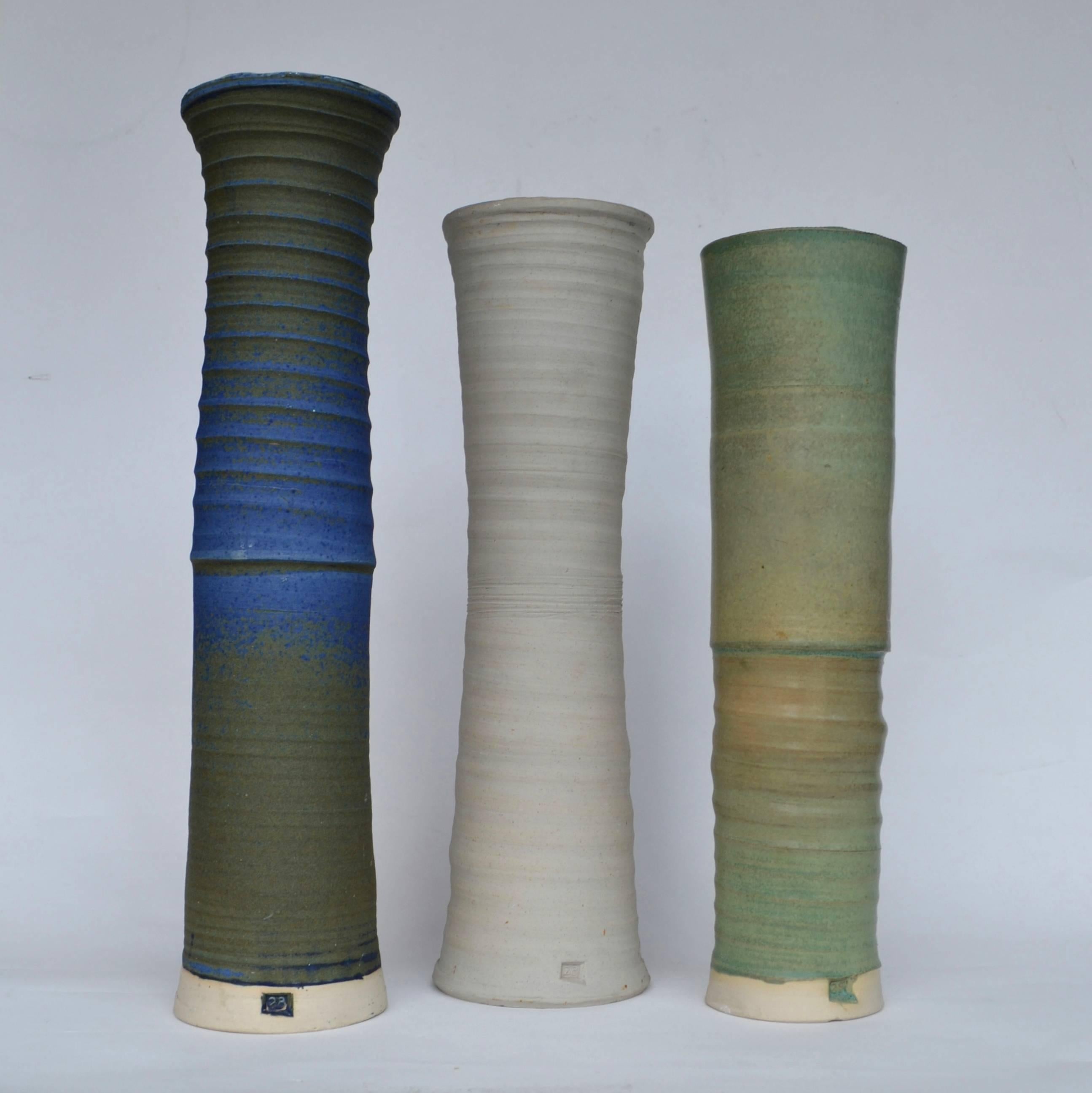 Vases ou récipients allongés dans des tons sourds de bleu, de vert et de sable par la céramiste britannique Virginia Rood Pane.
Ils ont des hauteurs (49, 44, 42 cm) et des formes légèrement différentes et les textures montrent le mouvement de la