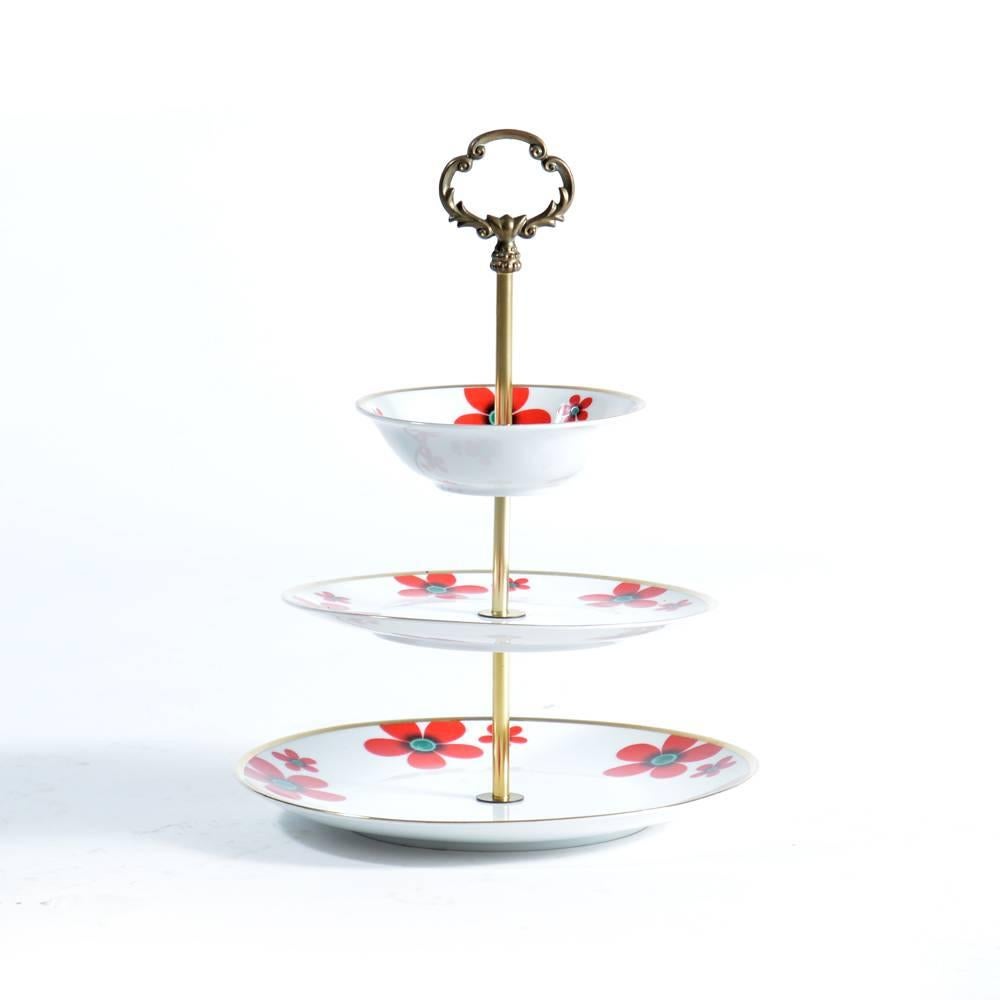 Beautiful item with lots of style. Typical cake stand design with three layers of porcelain plates. Plates in excellent condition with beautiful flowers and hand painted gold rim. The middle stick is in brass with beautiful details. Excellent