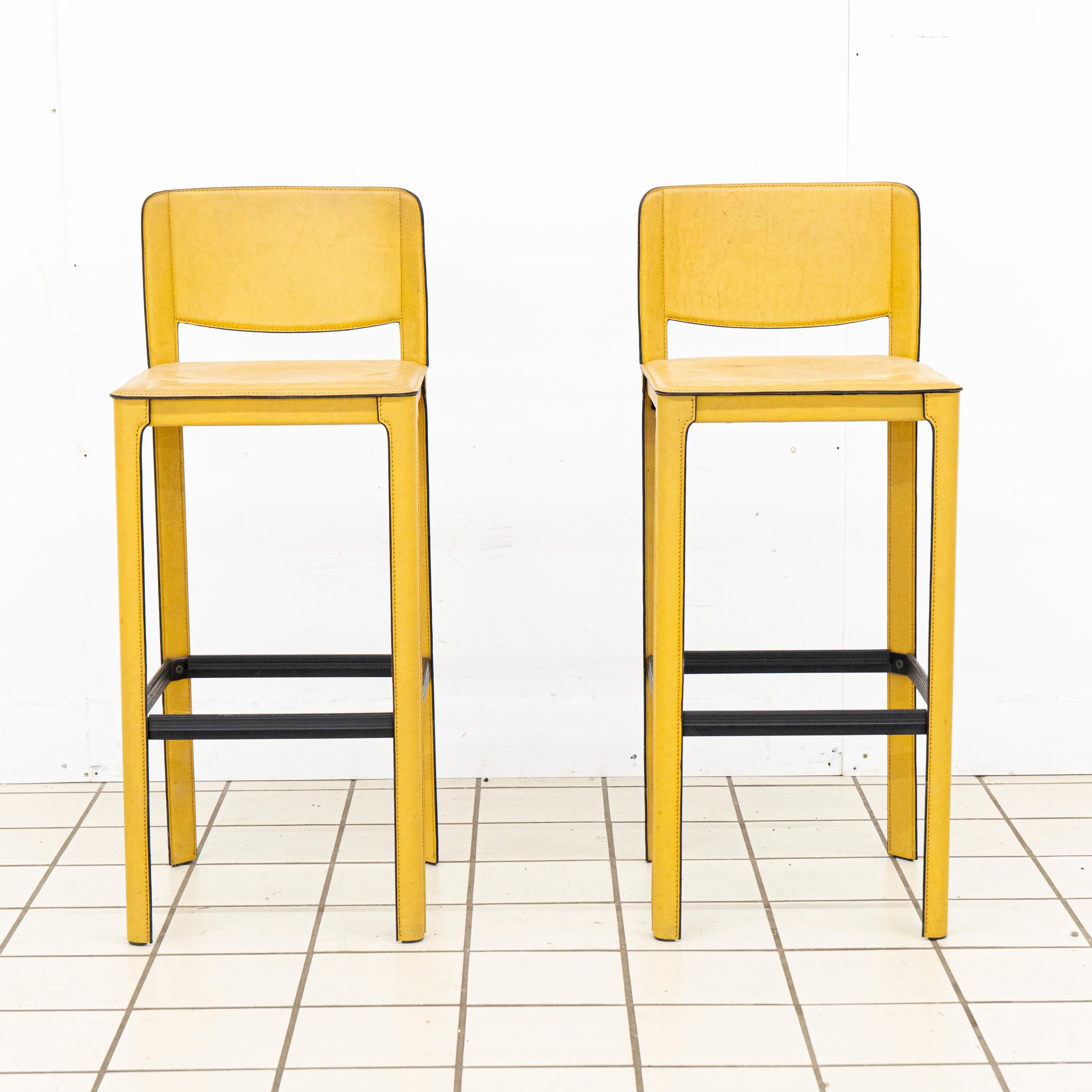 Este par muestra el equilibrio característico de Agnoli entre sencillez, proporción y calidad de los materiales. Envueltos en flexible cuero amarillo mostaza, los taburetes combinan una cálida expresión con una silueta limpia y arquitectónica. El