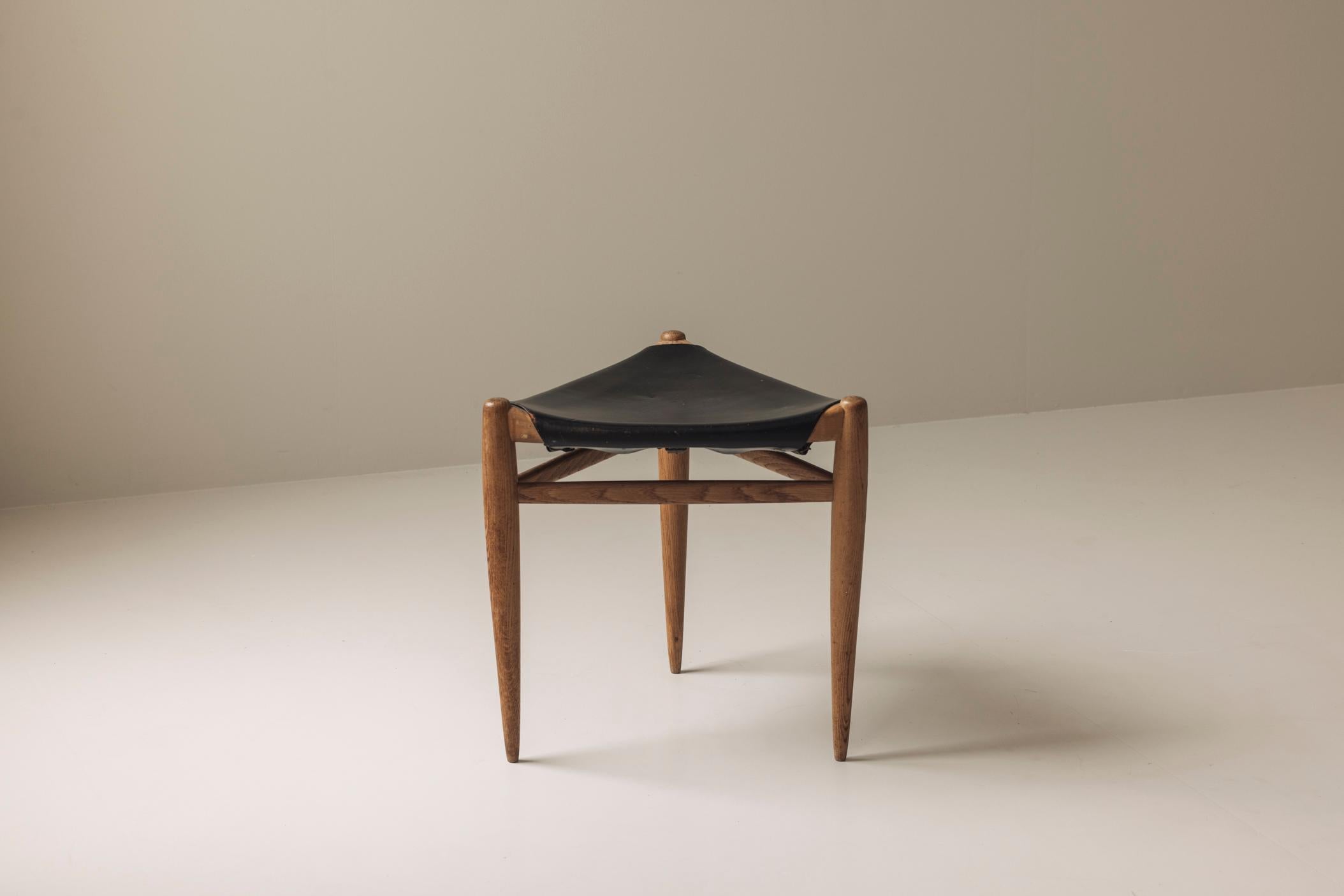 Ein auffälliges skandinavisches Design von Uno & Östen Kristiansson. Dieser seltene dreibeinige Hocker wurde in den 1960er Jahren von Luxus in Vittsjö hergestellt. Das aus massiver Eiche gefertigte und mit schwarzem Leder gepolsterte Möbelstück