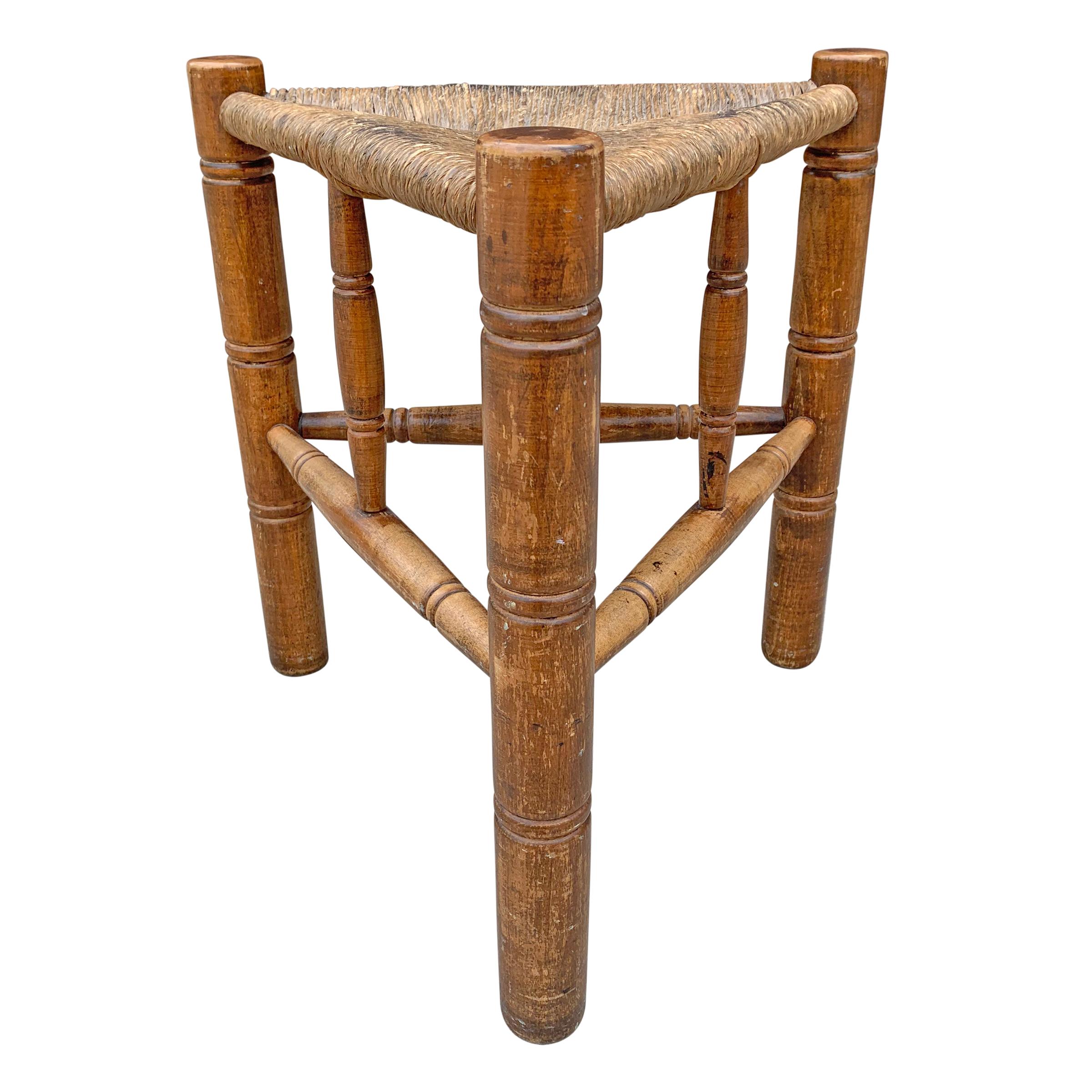 A wonderful early 20th century American three-legged stool with turned legs and stretchers, and a woven rush seat. Marked 