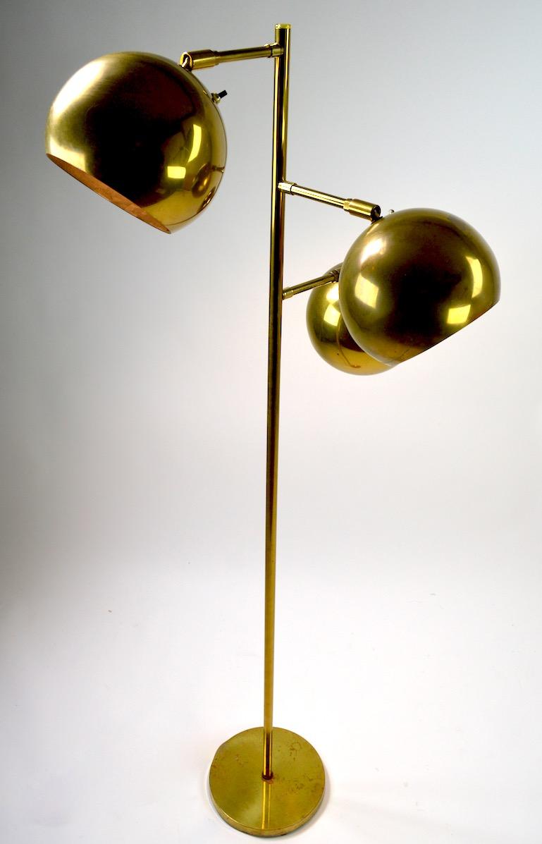 Three-light floor lamp in brass with ball form globe shades, which pivot to direct the light. Each shade has an on/off switch allowing independent operation of each light. Nice quality construction, brass finish shows some wear, and signs of age and