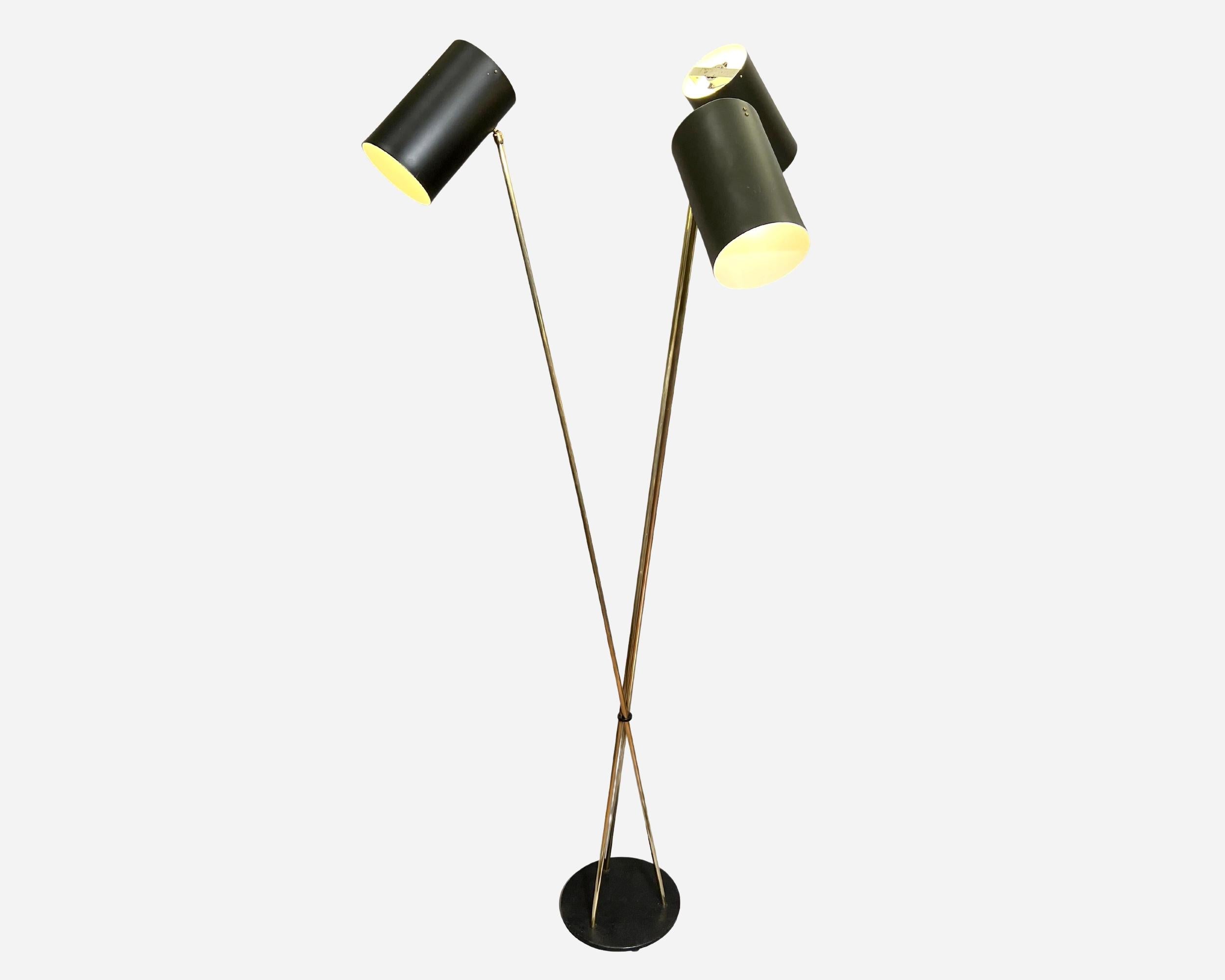 Large 1950’s floor lamp in the spirit of the Maison Lunel, made in France.
Three interlocking polished brass rods are fixed to a black lacquered metal base and support three adjustable shades (on ball joint) in black lacquered sheet metal with white