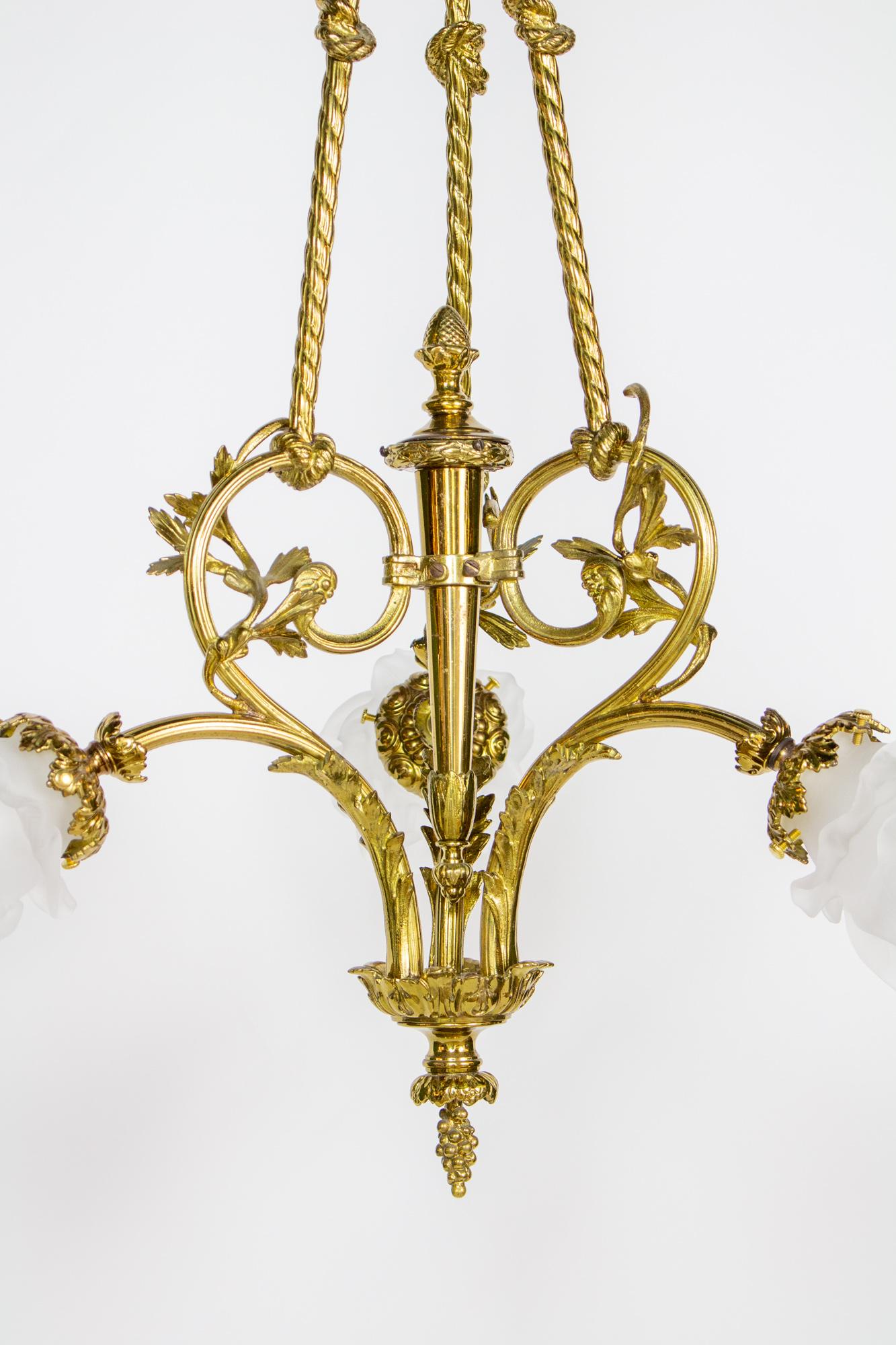 Brass chandelier in the shape of ropes and bows. Flower shaped glass shades. Louis XIV style. Completely restored and rewired, ready to install. includes glass flower petal shades in excellent condition.