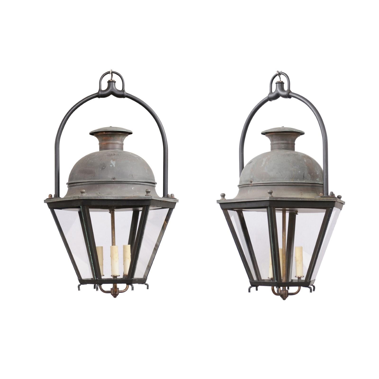 Two French hexagonal copper lanterns from the 20th century with glass panels, domed tops and three lights. Adorn your home with the captivating allure of these two French hexagonal copper lanterns from the 20th century, each sold individually. Their