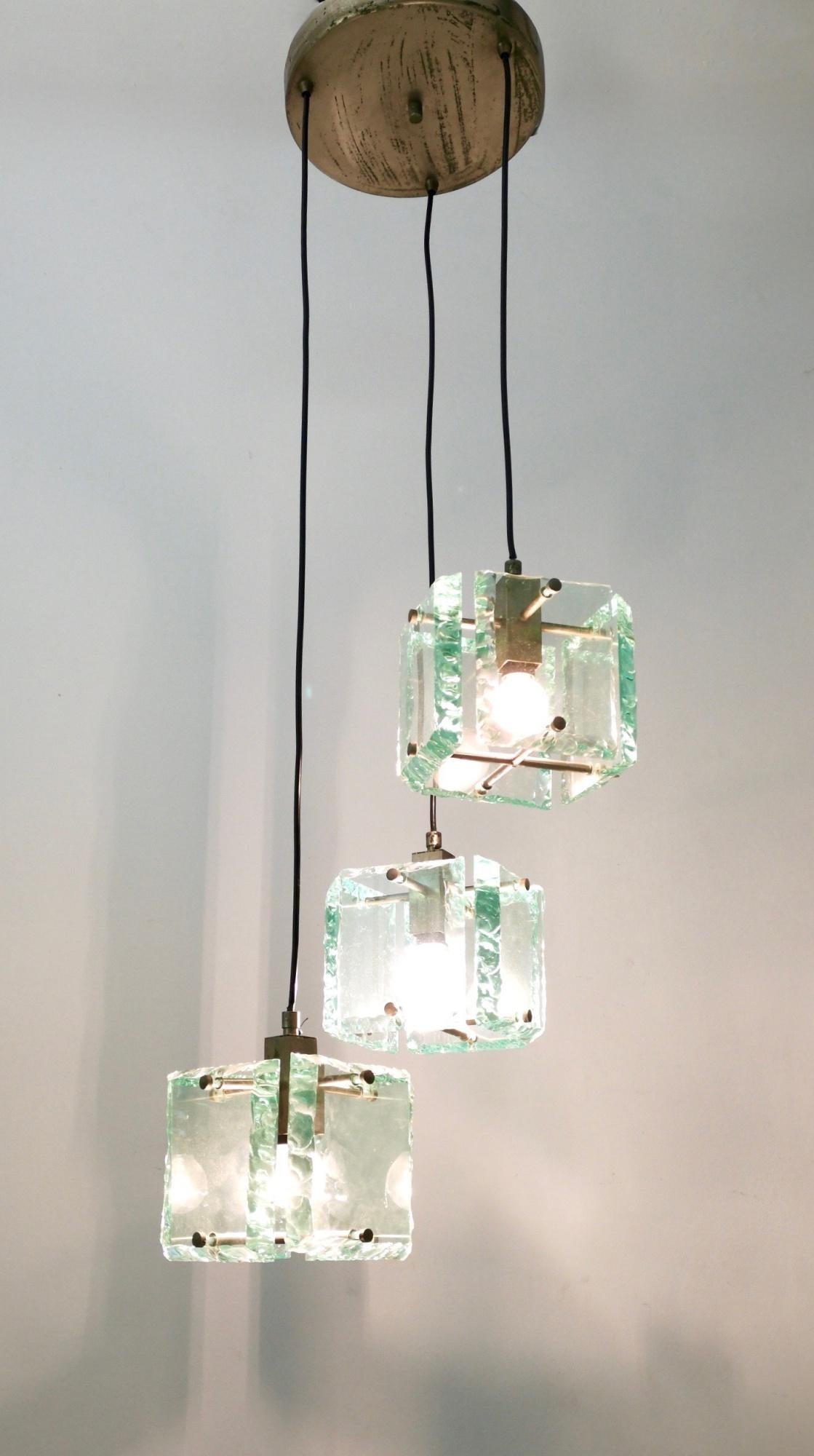 Made in Italy, 1960s. 
This pendant features thick Nile green hammered glass lampshades and varnished metal parts.
The metal parts may show slight traces of oxidation, but no rust, while the glasses are in excellent original condition.
Overall, it's