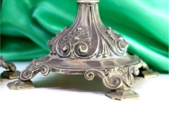 Three-light silver candelabra with shells and garlands resting on raised bases