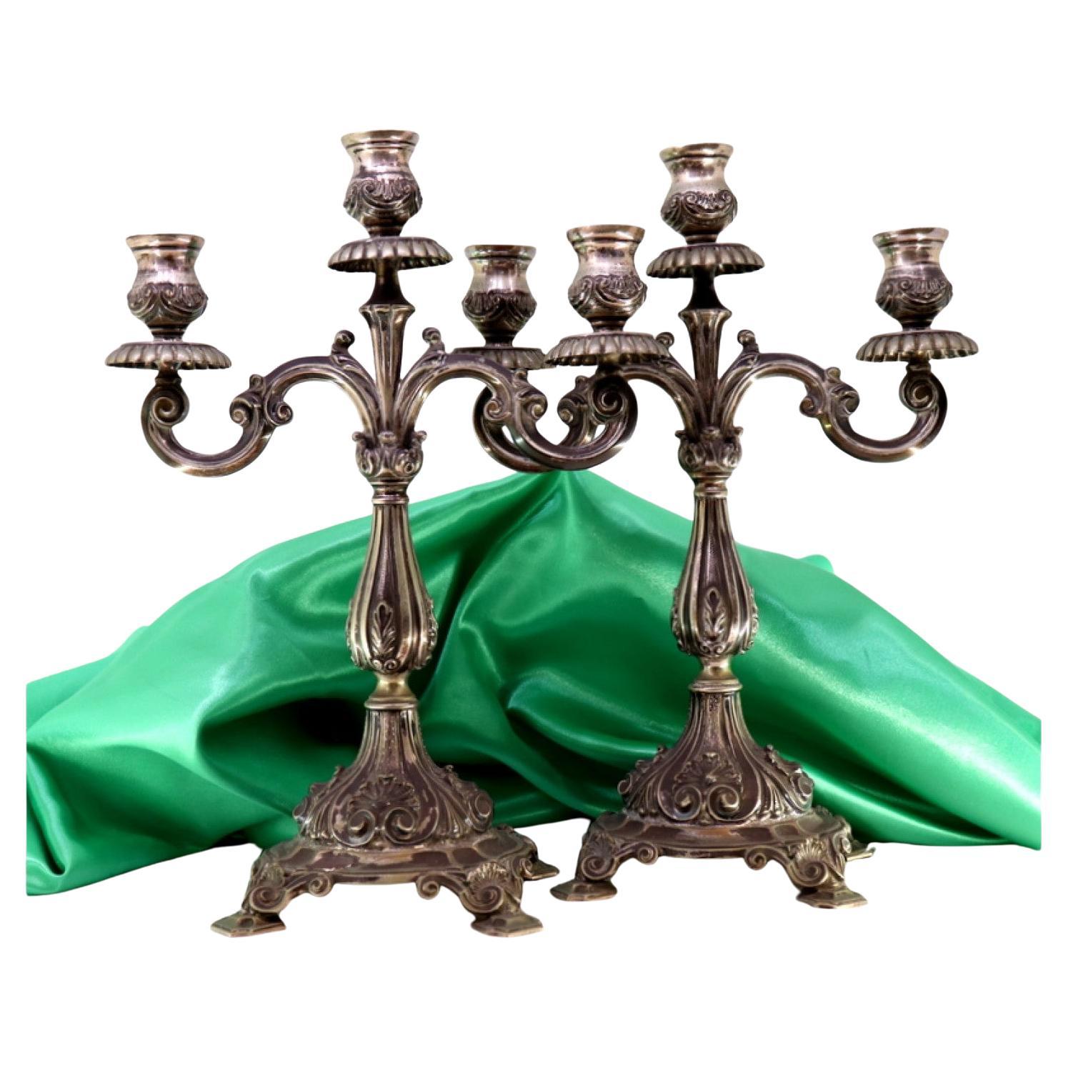 Three-light silver candelabra with shells and garlands resting on raised bases