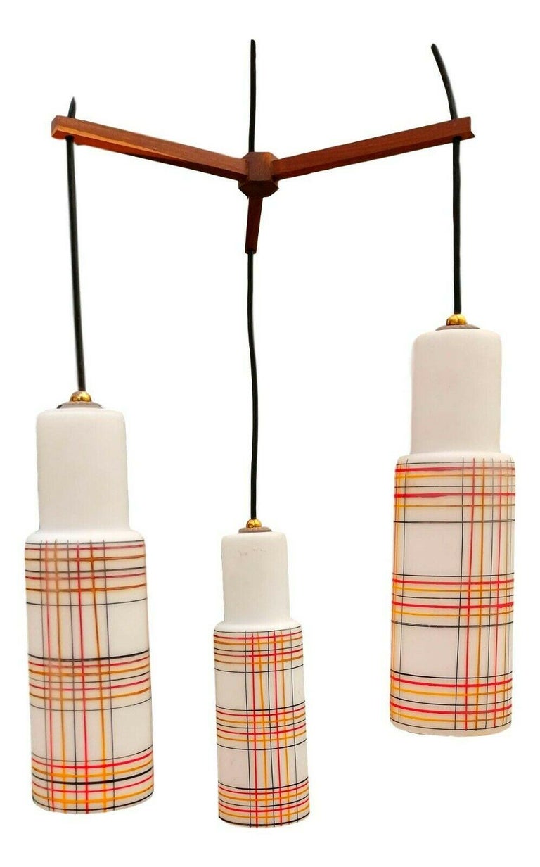 Original chandelier from the 1960s, attributed to Stilnovo production, consisting of three diffusers in cased murano glass and decorated with geometric designs in shades of yellow, red and black, together connected to a small triangular wooden