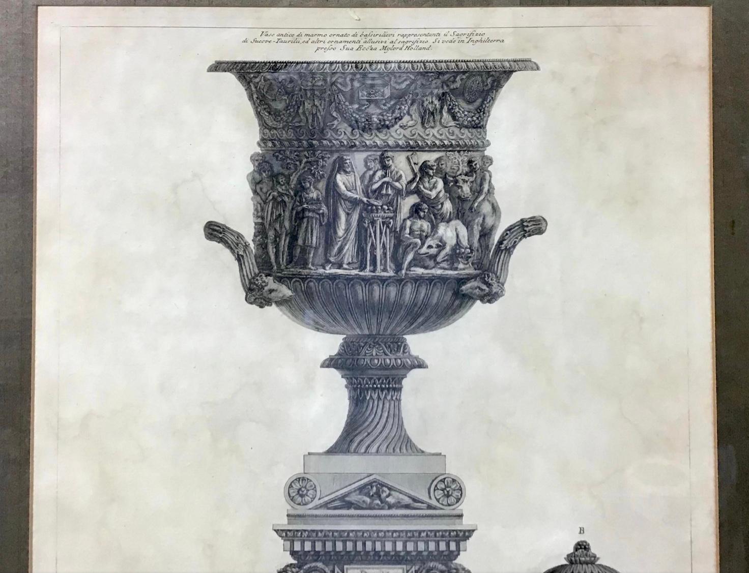 The central vase is carved with a priest and worshippers sacrificing the suovetaurilia (a boar, a ram and a bull), and is placed on a sarcophagus guarded by winged sphinxes. The left vase is carved with two birds eating grapes or berries, and the
