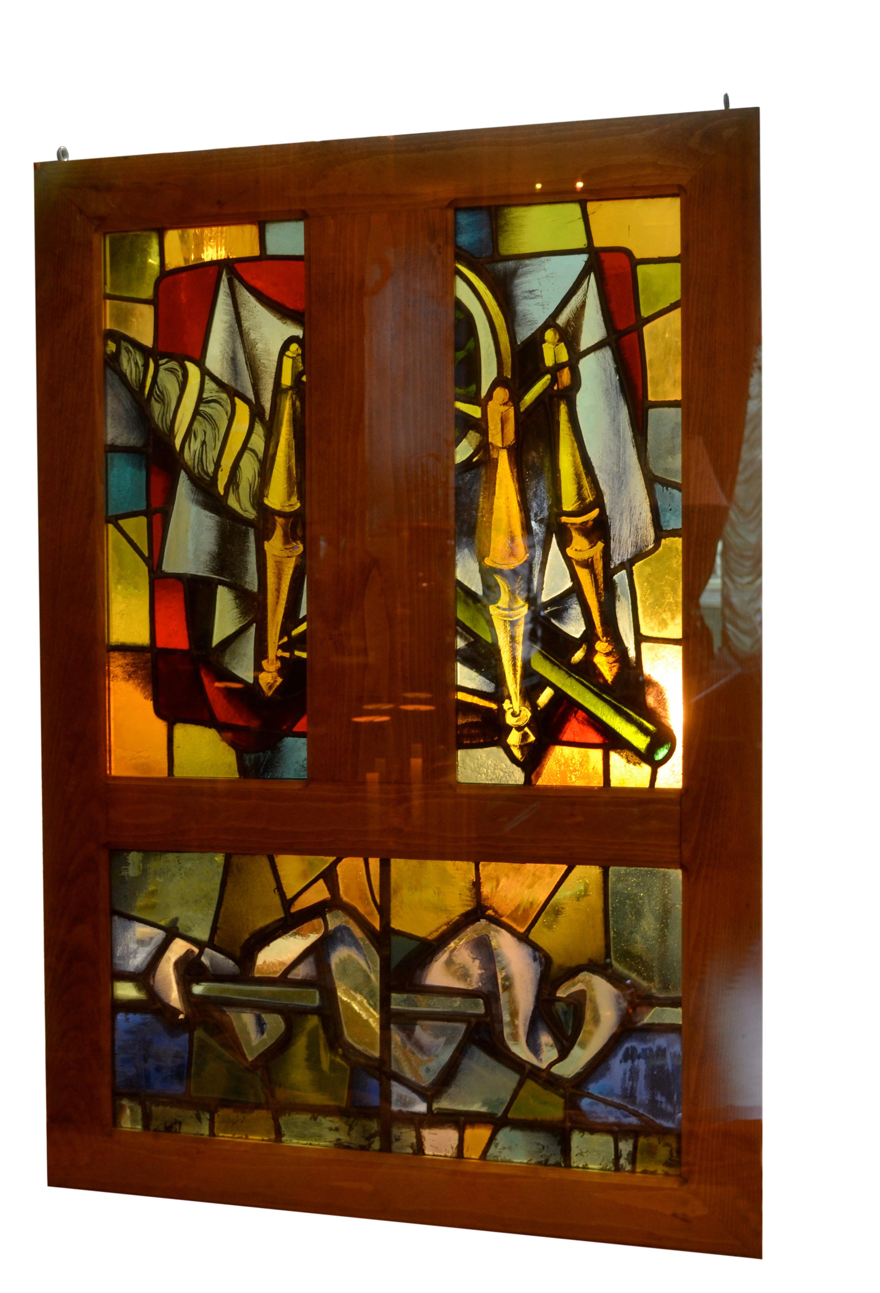 Three matching stained glass windows set in wooden frames and each comprised of two vertical contagious stained glass panels all three with different subjects over a horizontal stained glass panel that is identical for all three windows. These