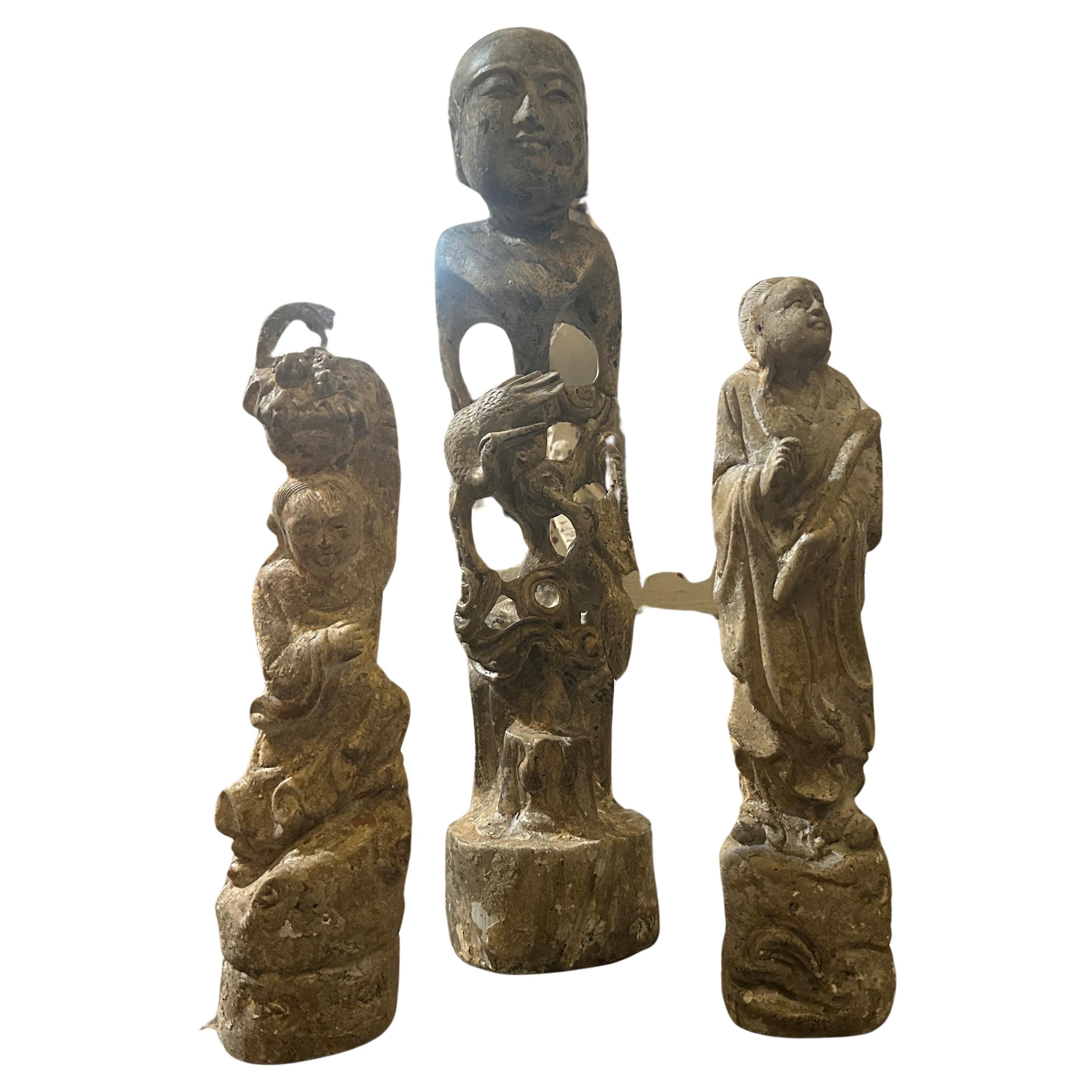 Three hand-carved wood chinese figures with a patina that makes them look like stone in good conditions with just signs of age. The finish applied to the wood that mimics the appearance of stone. This involves mottled surface treatment, giving the