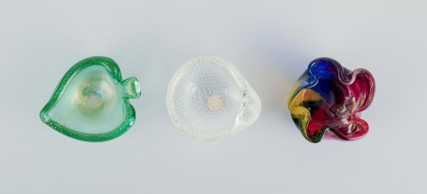 Trois bols en verre d'art de Murano
Verre polychrome, verre transparent avec bulles et verre vert avec poussière d'or.
Vers les années 1970.
Un avec un Label.
En parfait état.
Bol vert : L 9,0 cm x L 7,2 cm x H 3,0 cm.

