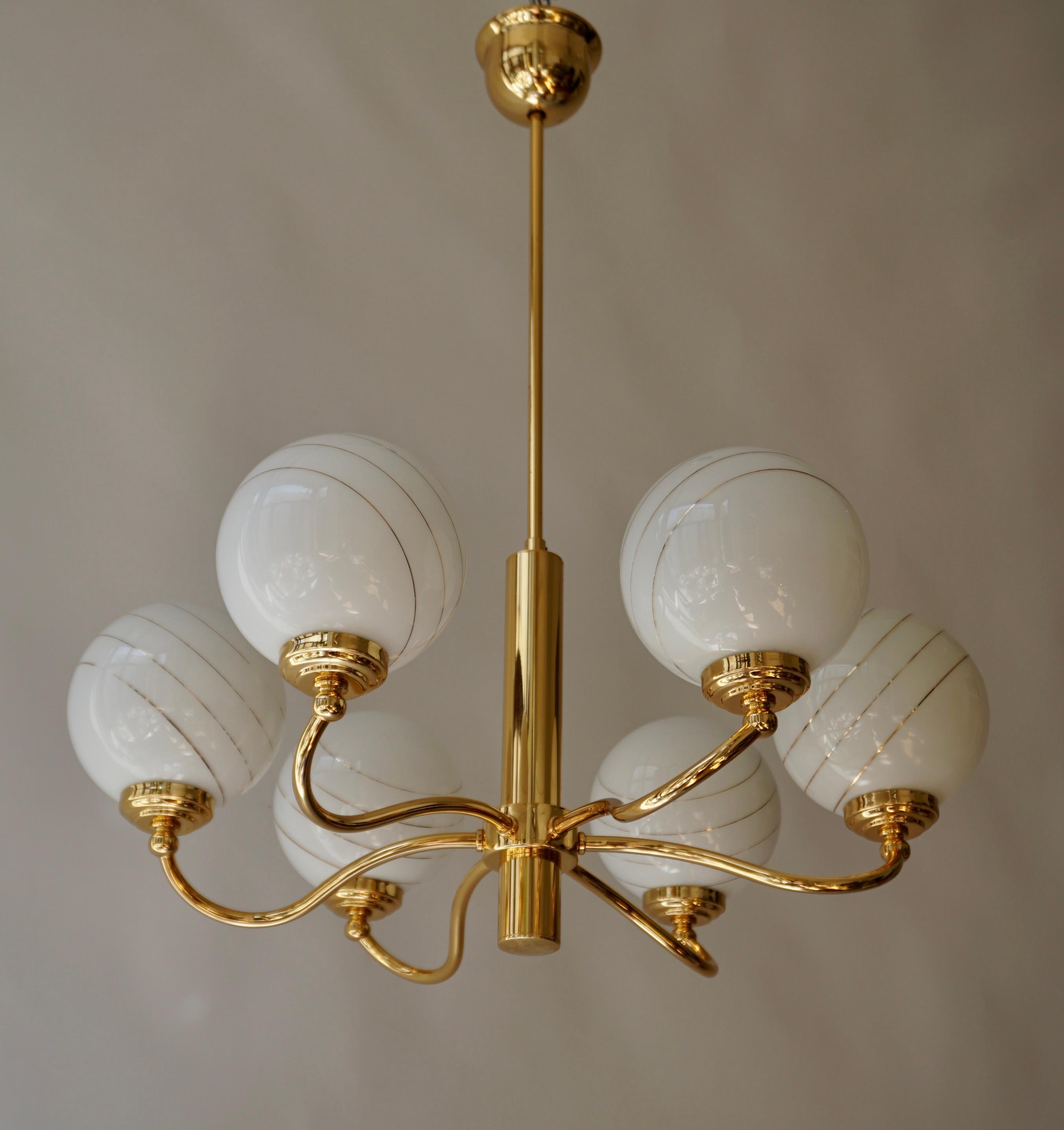 Three Italian Murano glass and brass six-arms chandeliers.  
Balloon brass chandelier with 6 large white glass opaline spheres with gold stripes and brass fixture.

Measures: 
Diameter 23.6
