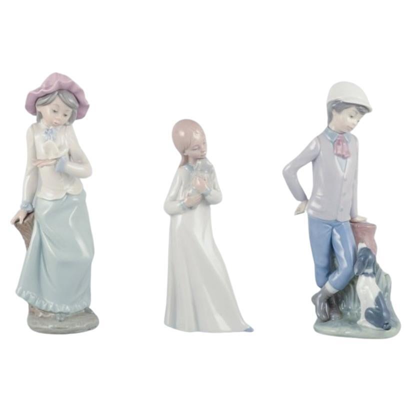 Trois figurines en porcelaine de Nao. Garçons et filles avec animaux de compagnie. 