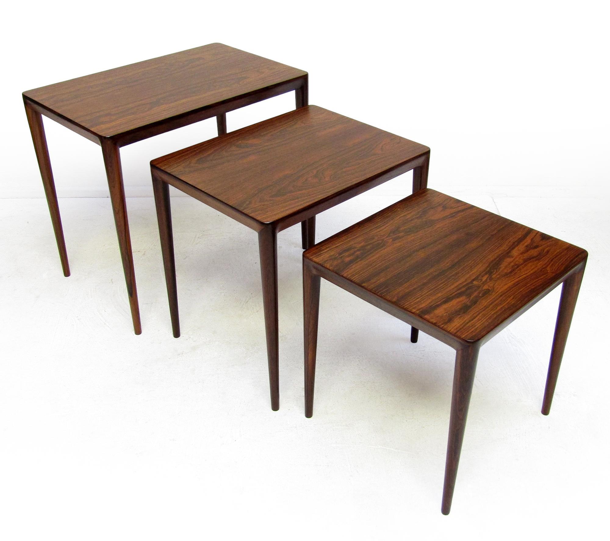A set of three elegant nesting tables in rosewood by Erik Riisager Hansen for Danish makers Haslev.

With finely rounded contours and striking corner joins, they stand on slender, tapered legs. The Rio rosewood is richly figured.

They bear the