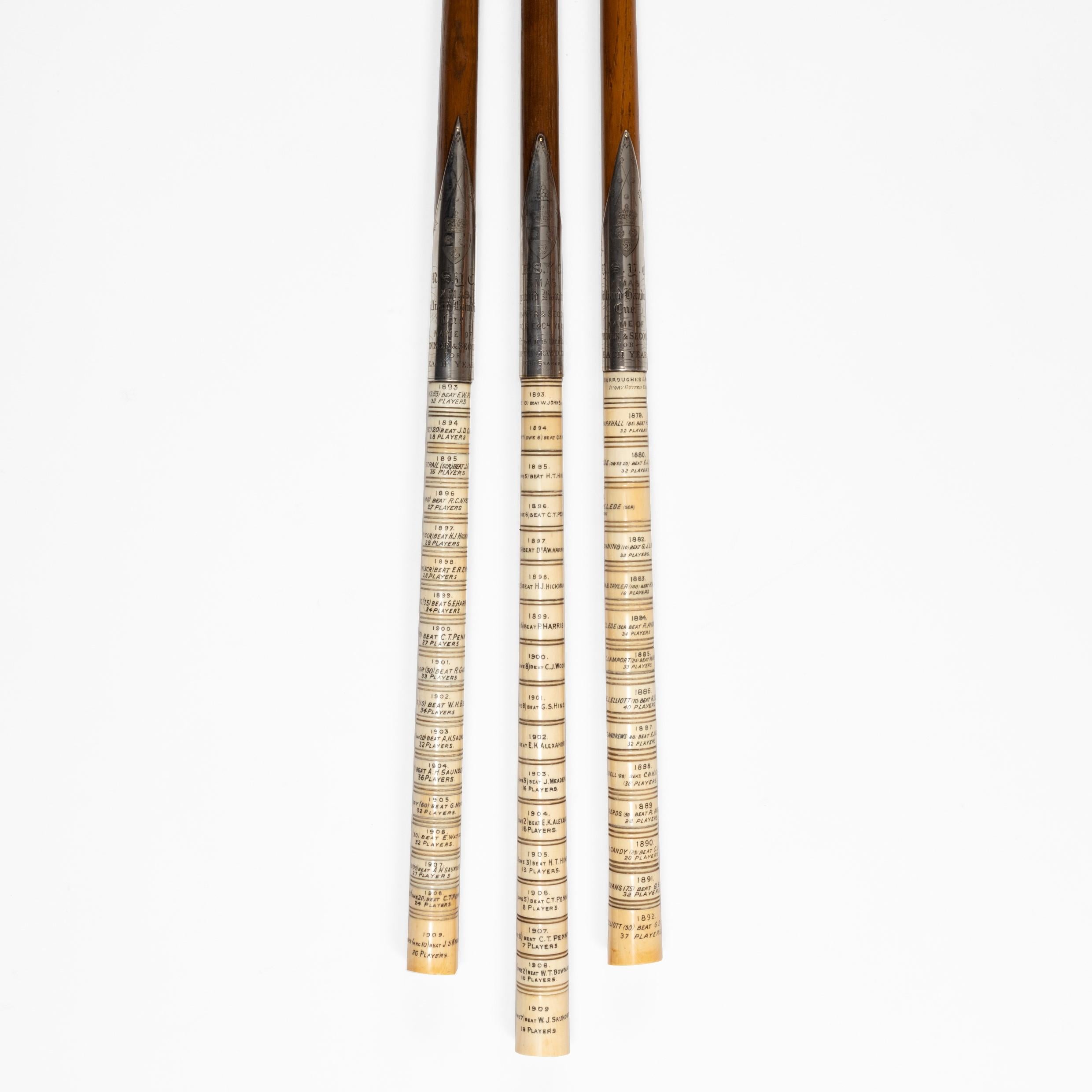 Three oak, silver and ivory trophy billiard cues, dated 1879-1909, the silver collars inscribed ‘R.S.Y.C. Christmas Billiards Handicap’ and ‘R.S.Y.C. Christmas Pyramid Handicap, Burroughes & Watts,’ and the handles comprising an ivory ring with the