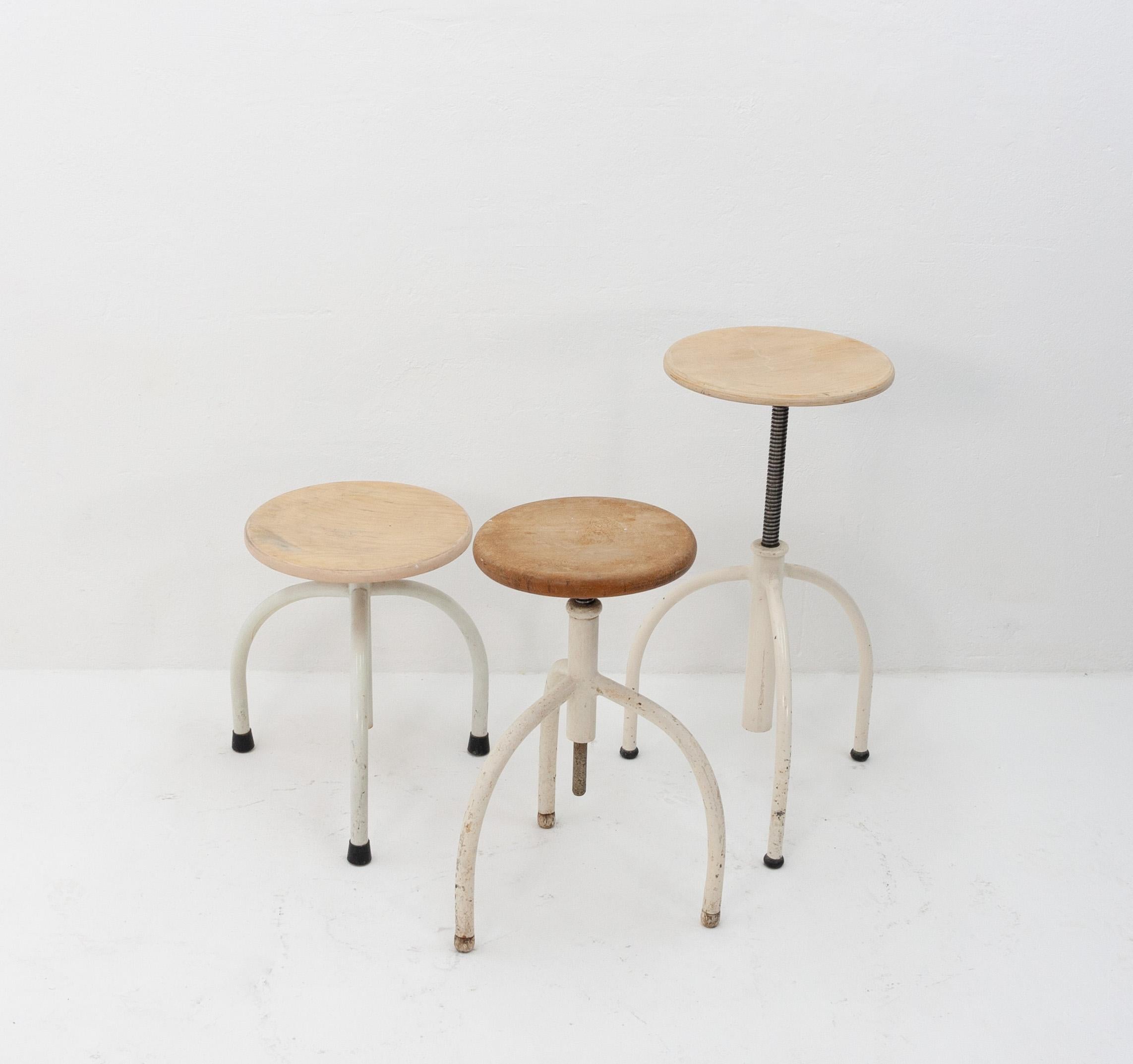 Three Oostwoud Franeker Holland, medical stools. Adjustable in height, Metal frame with solid wood top, 1950s. Was used in hospitals. Three leg stools. One is a little older. Good working condition.
   