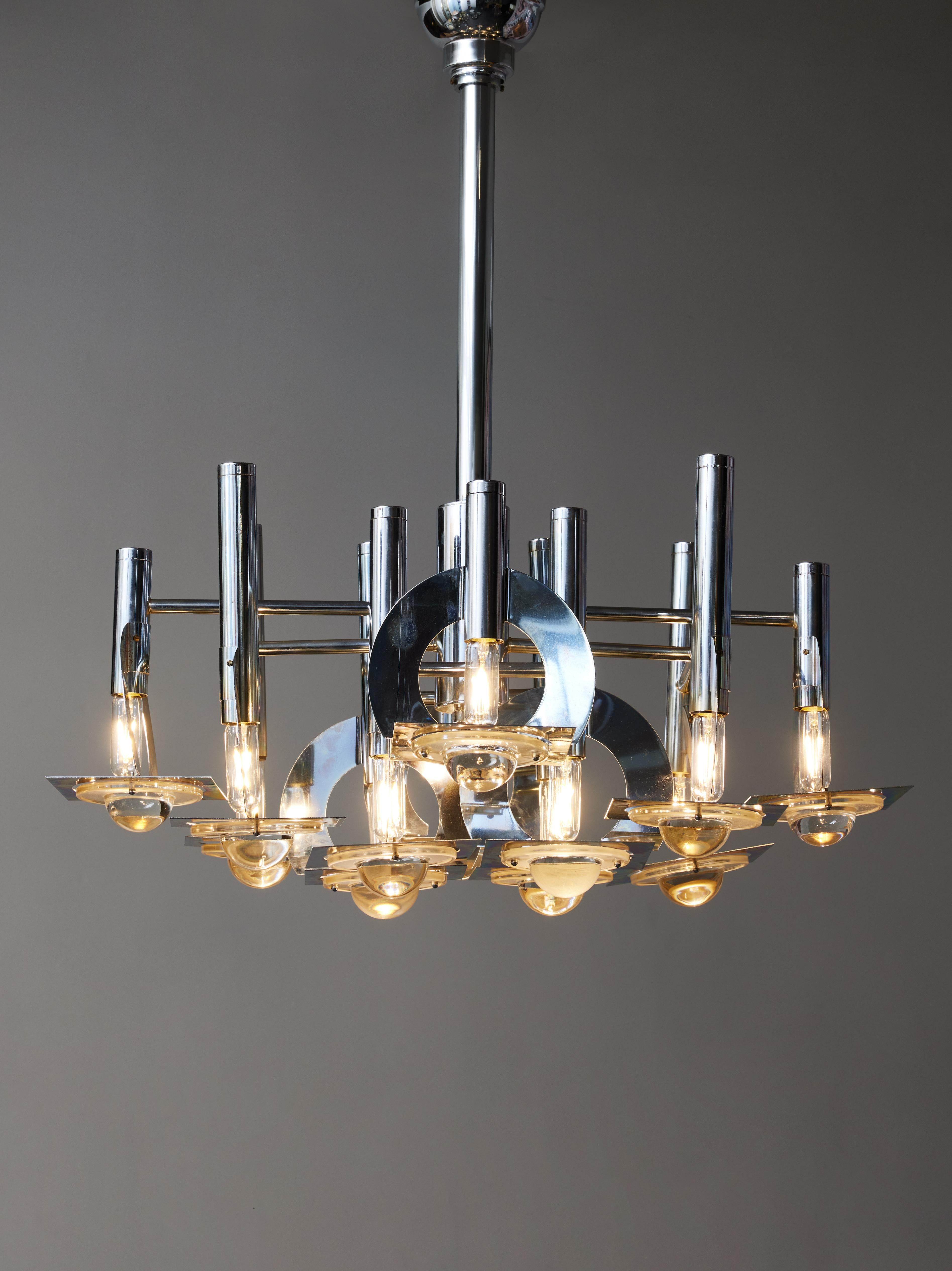 Three vintage chandelier by Oscar Torlasco for the manufacturer Lumi Milano, made of a steel structure, twelve ams of light and glass lenses diffusers.

Oscar Torlasco (1934-2004)
Oscar Torlasco is an Italian designer who concentrated most of his