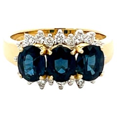 Anillo de tres zafiros azules ovalados y diamantes en oro amarillo de 18 quilates