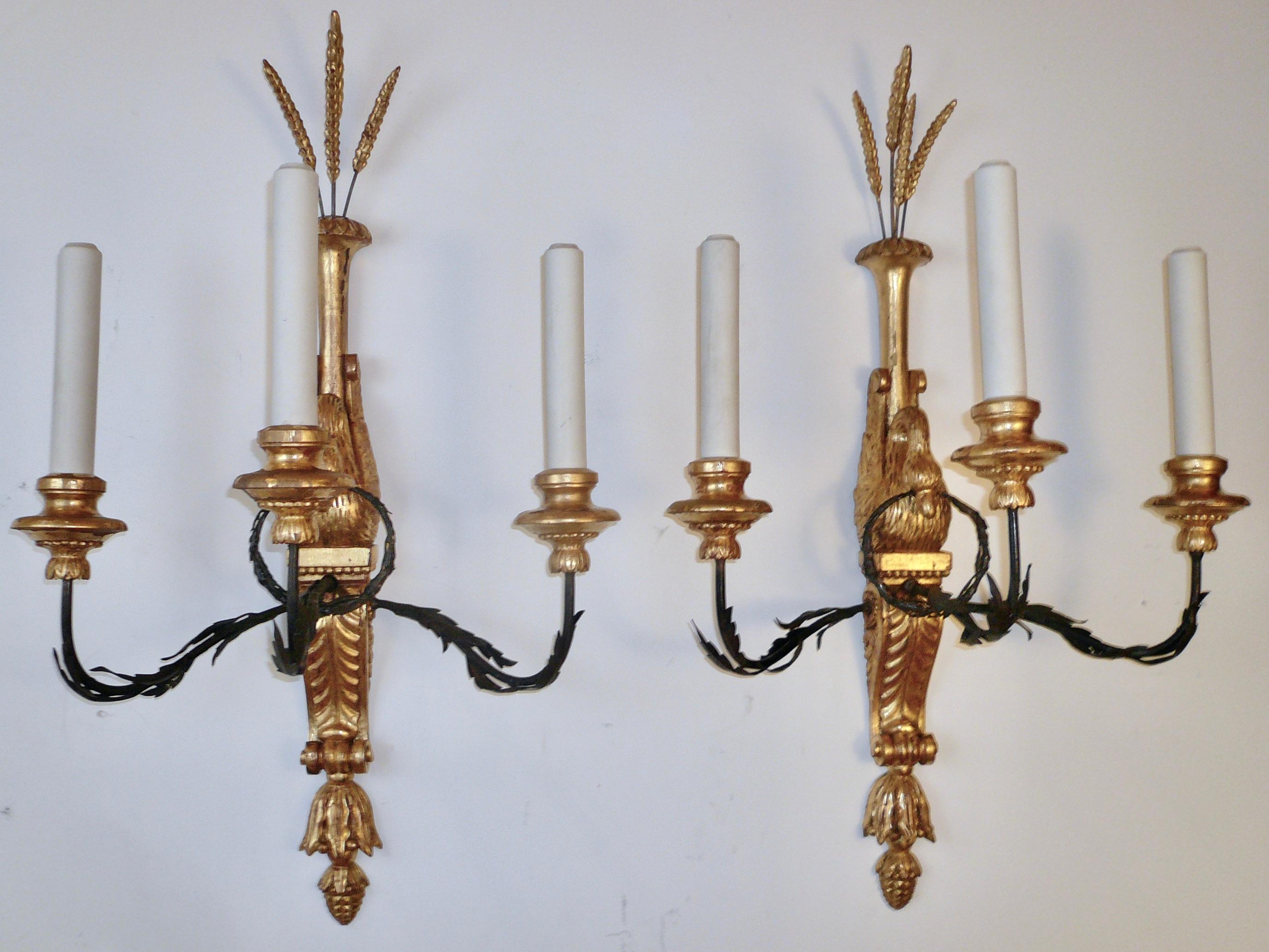This rare set of six signed sconces (sold by the pair), are hand carved and feature Classical motifs including bellflowers, acanthus leaves, and pinecone finials.
Each sconce consists of a carved giltwood swan holding an hand forged iron wreath in
