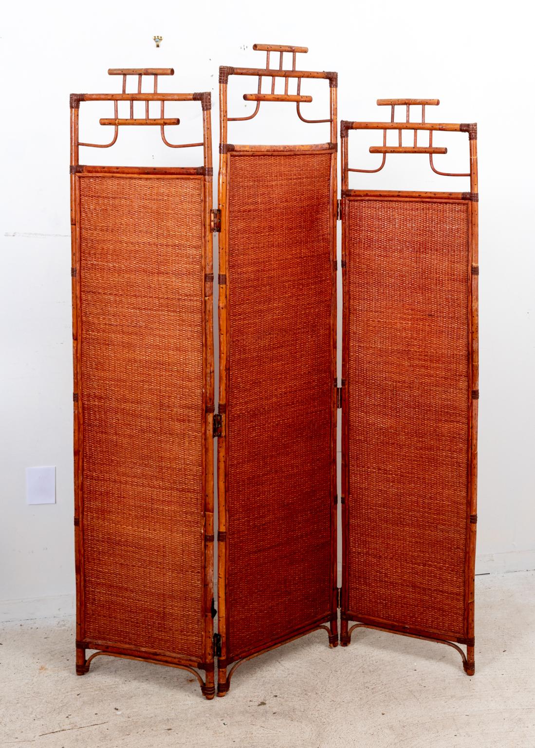 Circa 1990s three panel folding bamboo frame and rattan panel screen or room divider in the Hollywood Regency style. Please note of wear consistent with age. Good overall condition.