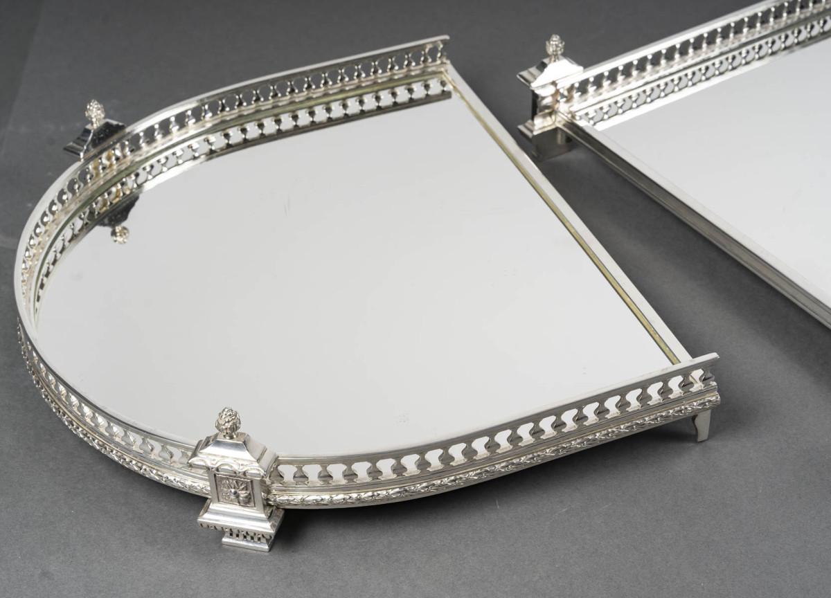 Three-part table centerpiece with a mirrored base, mounted on a wooden parquet floor, surrounded by an ingot mold forming an openwork gallery, punctuated by columns, topped with a pine cone.

Dimensions: Length 120 cm – Central width 44 cm – Gallery