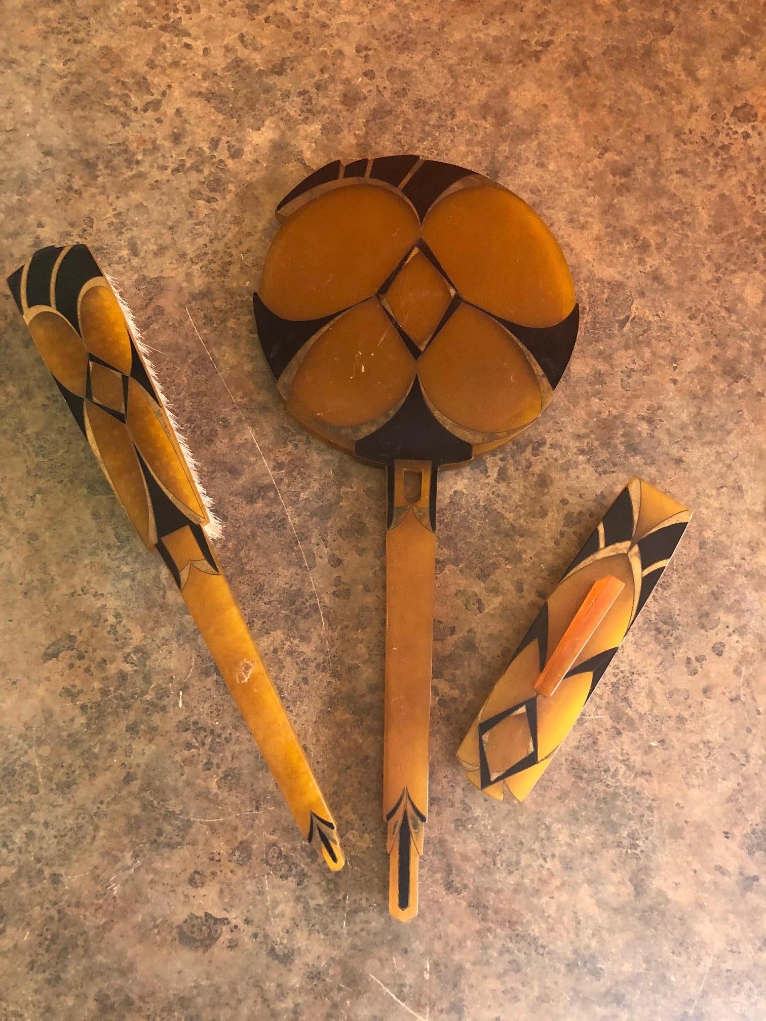 Three piece Art Deco vanity / dresser set which includes a hand mirror, hair brush and nail buffer by La Parfaite of France, circa 1930s. The set is made of agalin which is a close cousin to bakelite in is in good to fair vintage condition. There is