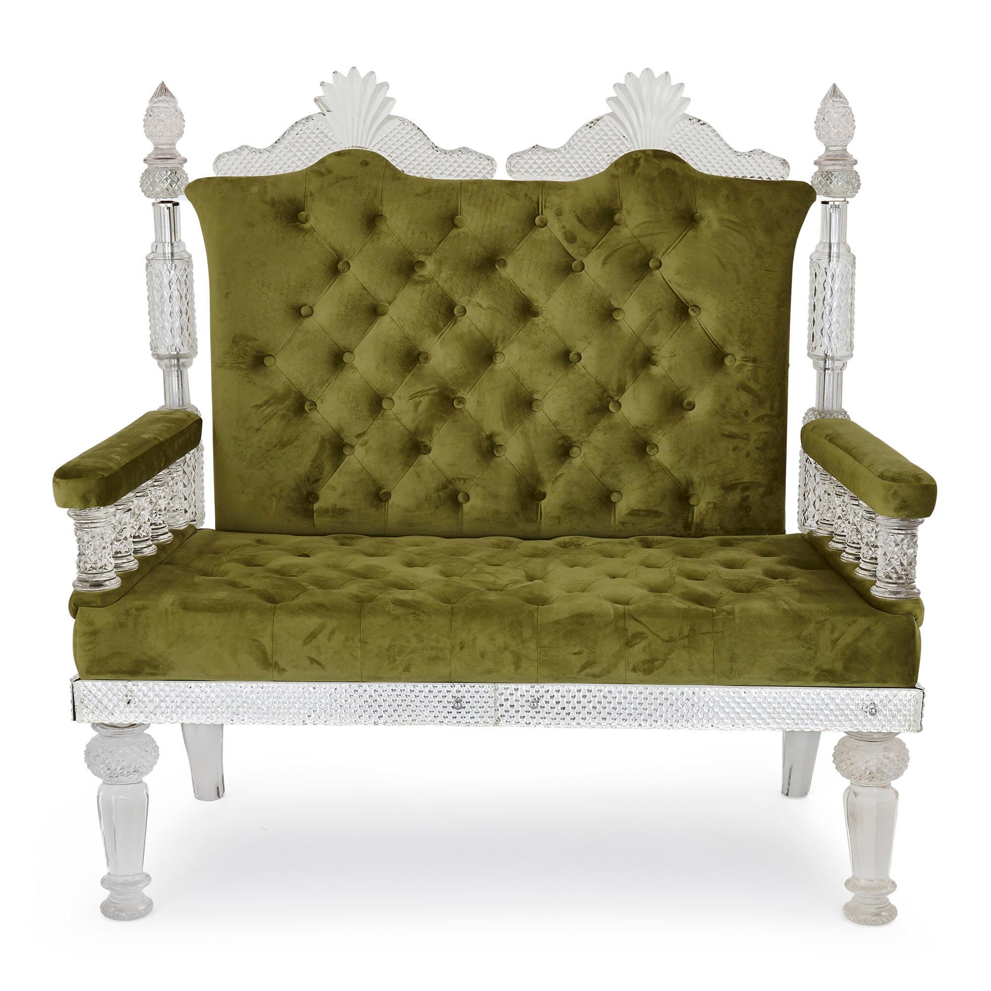 This three-piece suite of furniture contains a two-seat sofa and two armchairs. The pieces are formed from faceted cut glass and green velvet in the style of F&C Osler, an English glassmaking firm. Each piece is supported by four cut glass legs, the