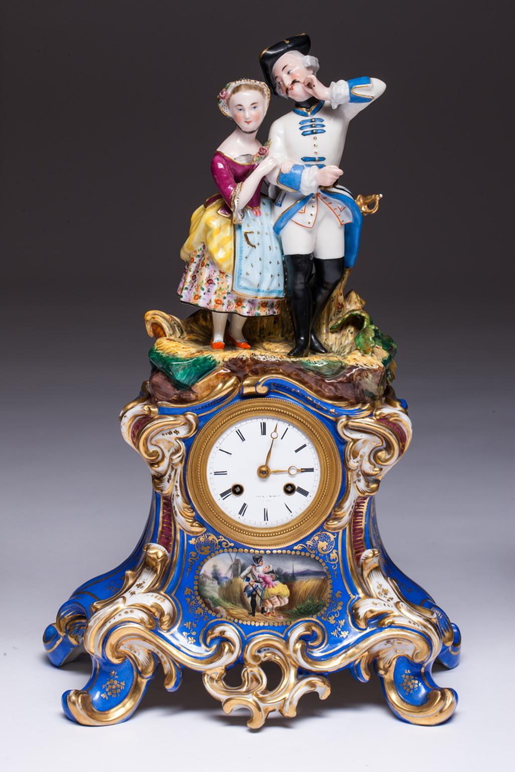 Three-piece old Paris porcelain mantel garniture in the rococo manner. A two-piece old Paris porcelain clock. The top half features a figures of a couple, soldier and a woman standing on the grass. The bottom half of the clock is painted with a