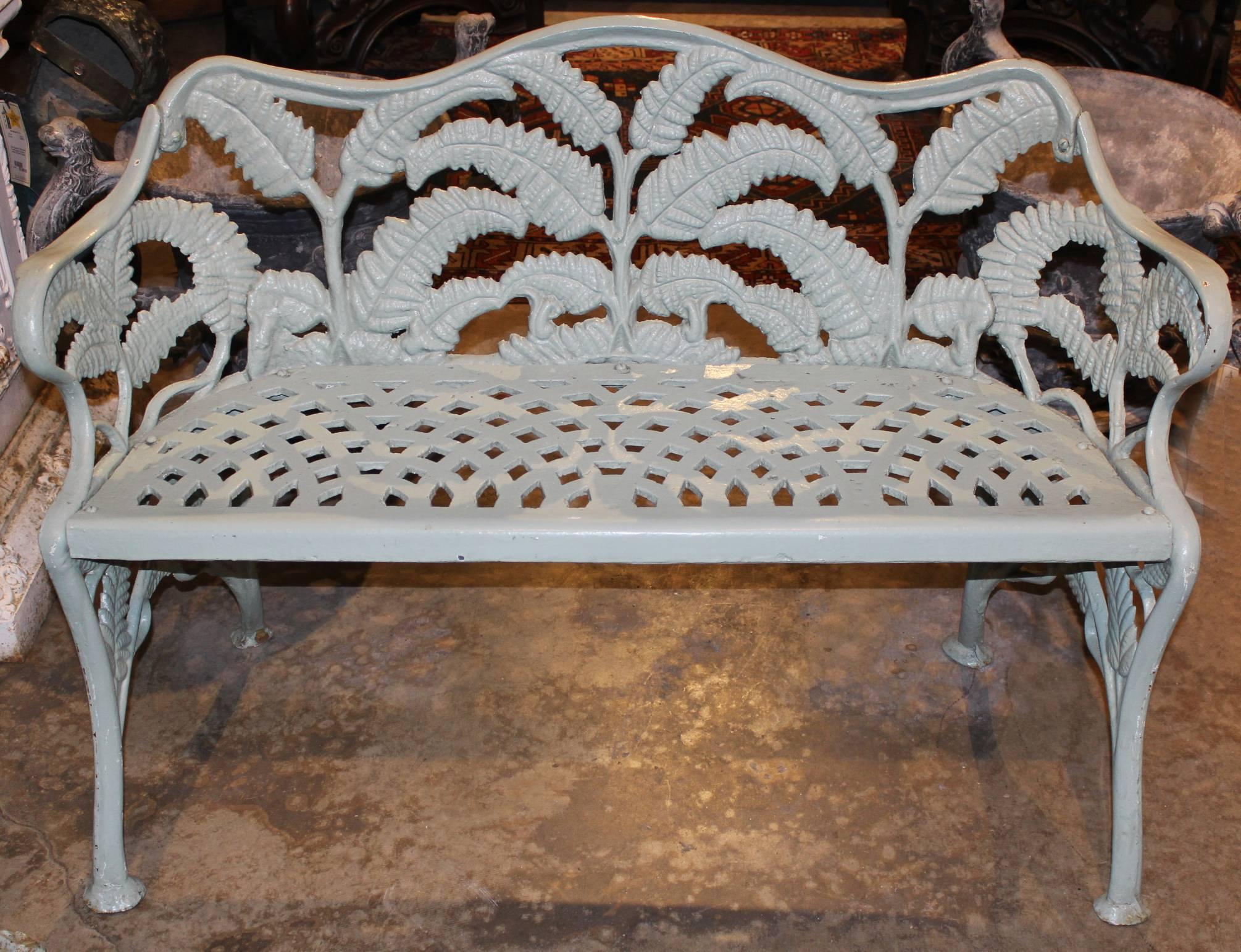 A heavy assembled set of cast iron garden furniture consisting of a Victorian settee and armchair with fern and scroll motif, along with a later round tripod side table with grapevine motif, all painted in celadon green,. Unsigned in very good