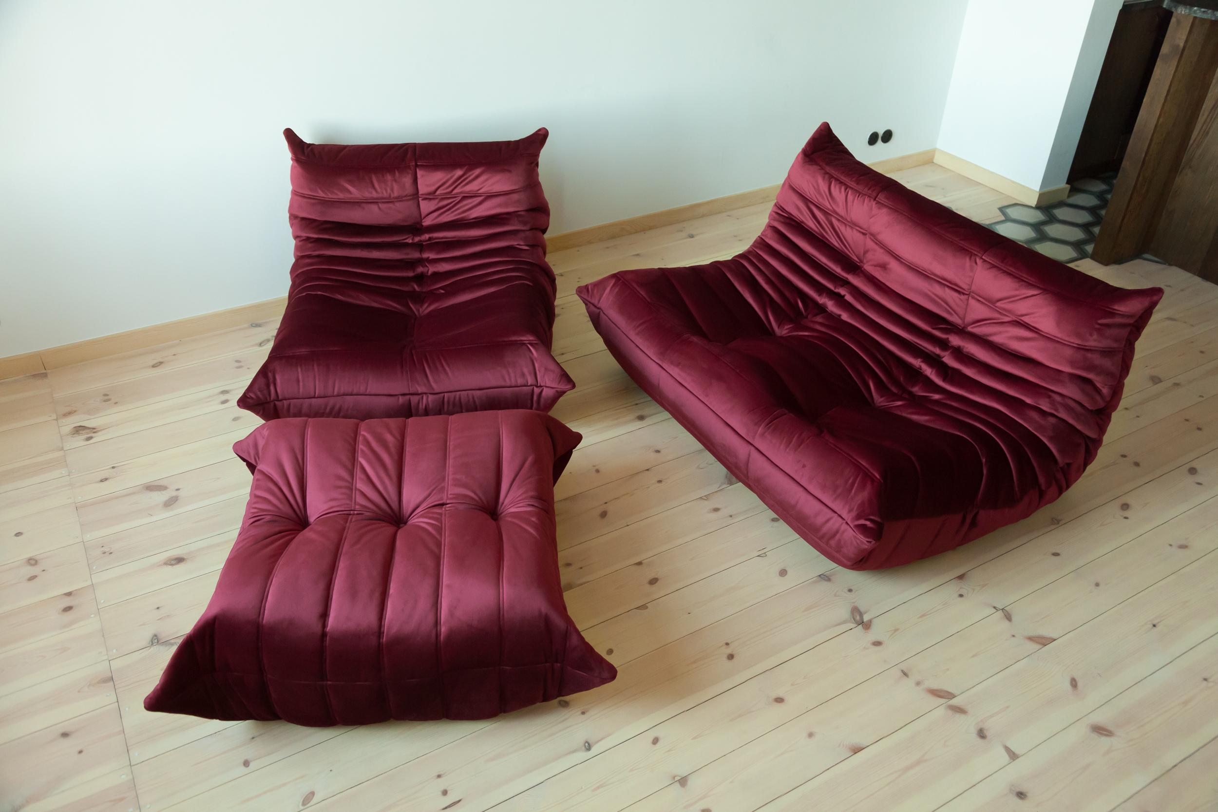 This Togo living room set was designed by Michel Ducaroy in 1973 and was manufactured by Ligne Roset in France. It has been reupholstered in burgundy high quality velvet, and is made up of the following pieces, each with the original Ligne Roset