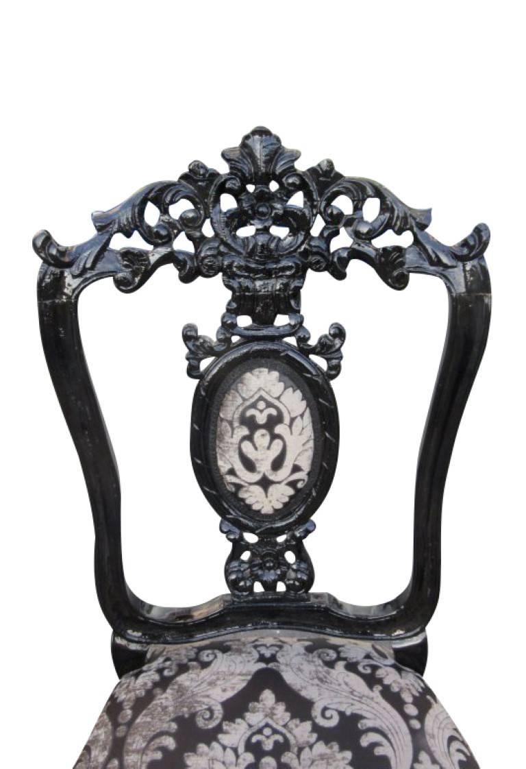 A set of chairs in Baroque style from circa 1900. The chairs were freed from the old paint and a new high gloss black was lacquered. These imposing big chairs strike with wonderful curved ornamentations and a beautiful black-white color play. The