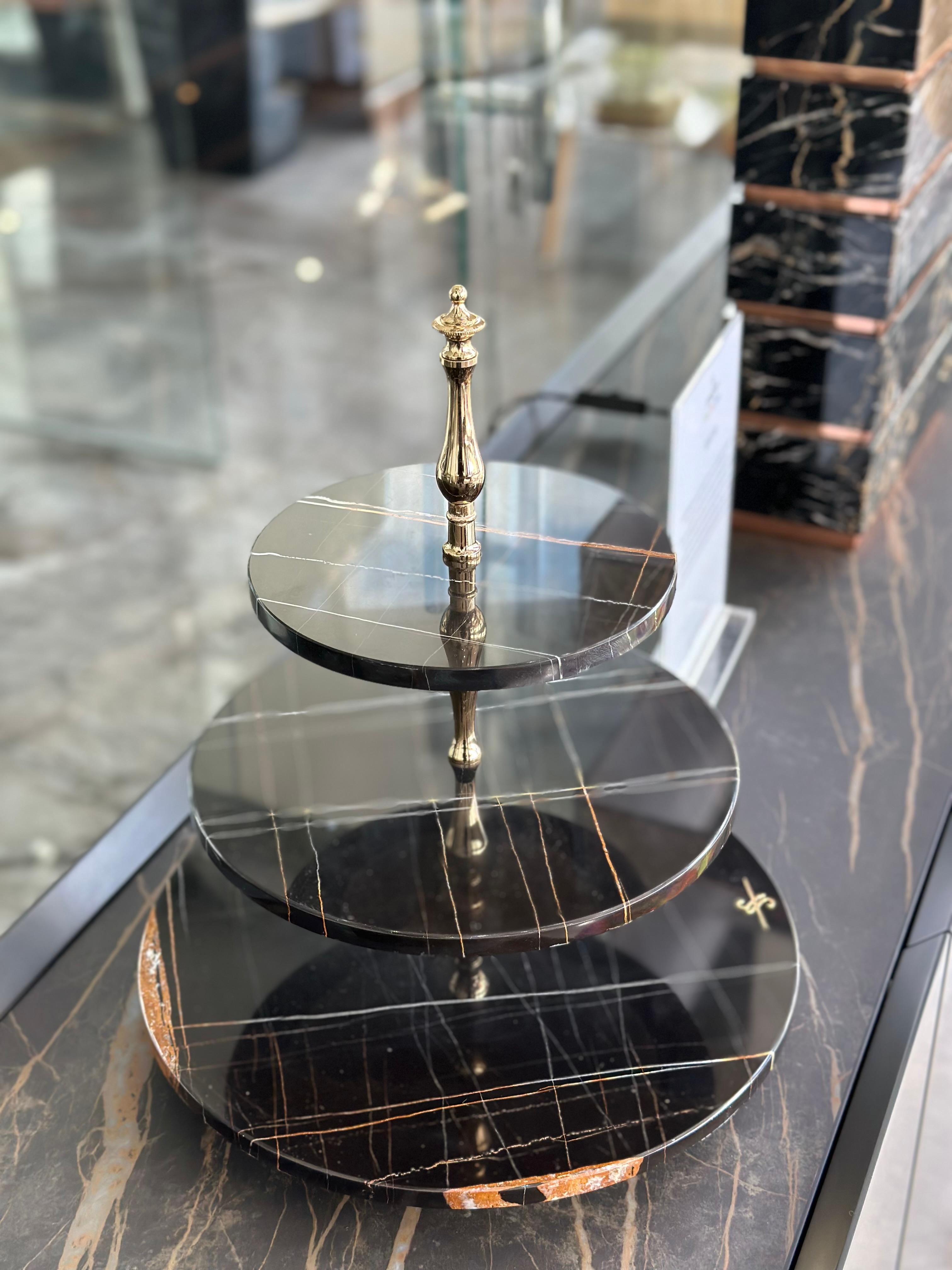 Cakestand aus Marmor mit drei Platten von Euromarmi Store
Abmessungen: T 33 x B 33 x H 38,5 cm
MATERIALIEN: Marmor Sahara Noir, 24 Karat vergoldet.

Der von Angela Stiuso gegründete Euromarmi Store entstand aus der Erfahrung und dem Engagement, das