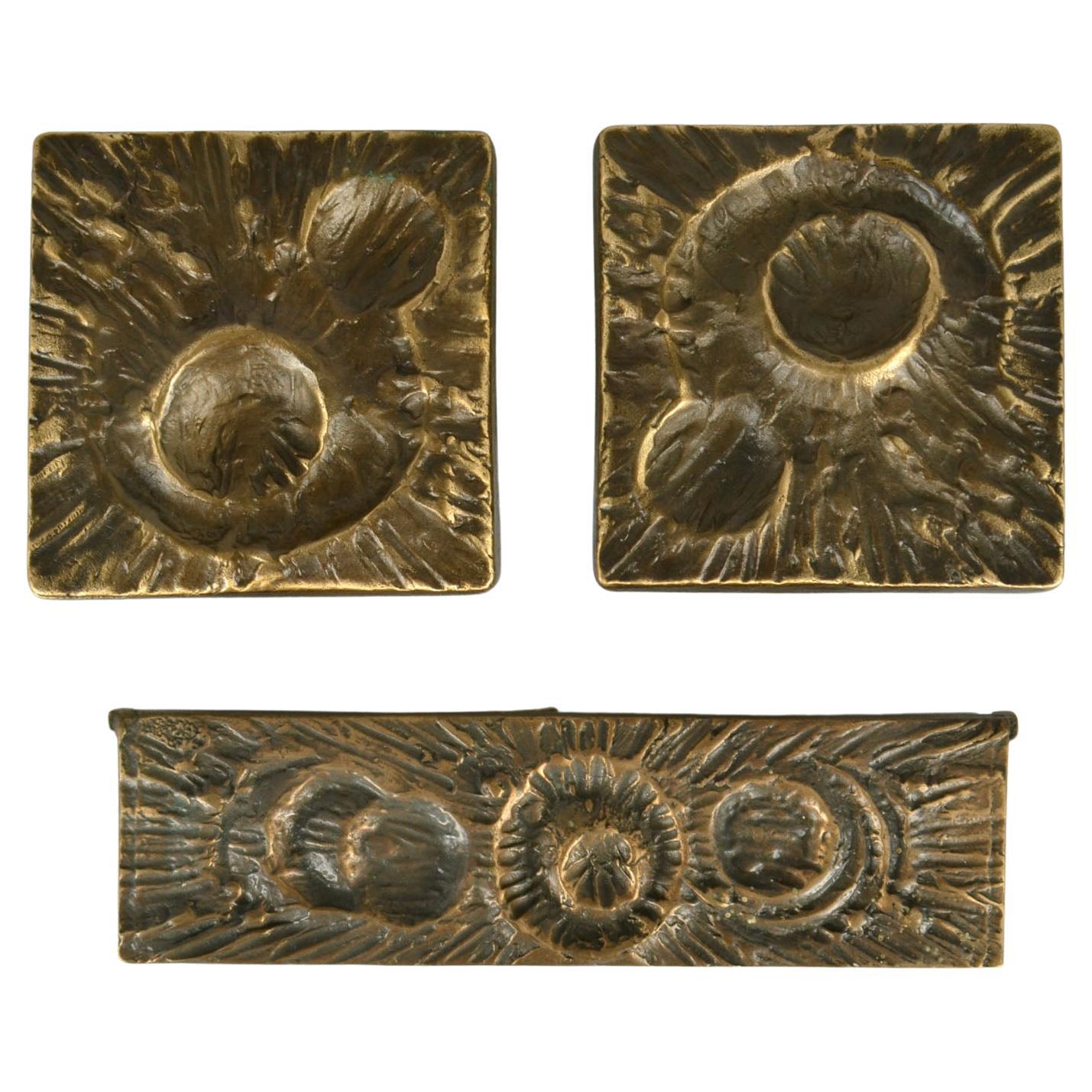 Two square cast bronze door handle and letter box with strong relief like craters in a landscape seen from above.
There is a third 
The handle brackets are attached to the main plate by two fixings. The handles are fitted to the door with two long