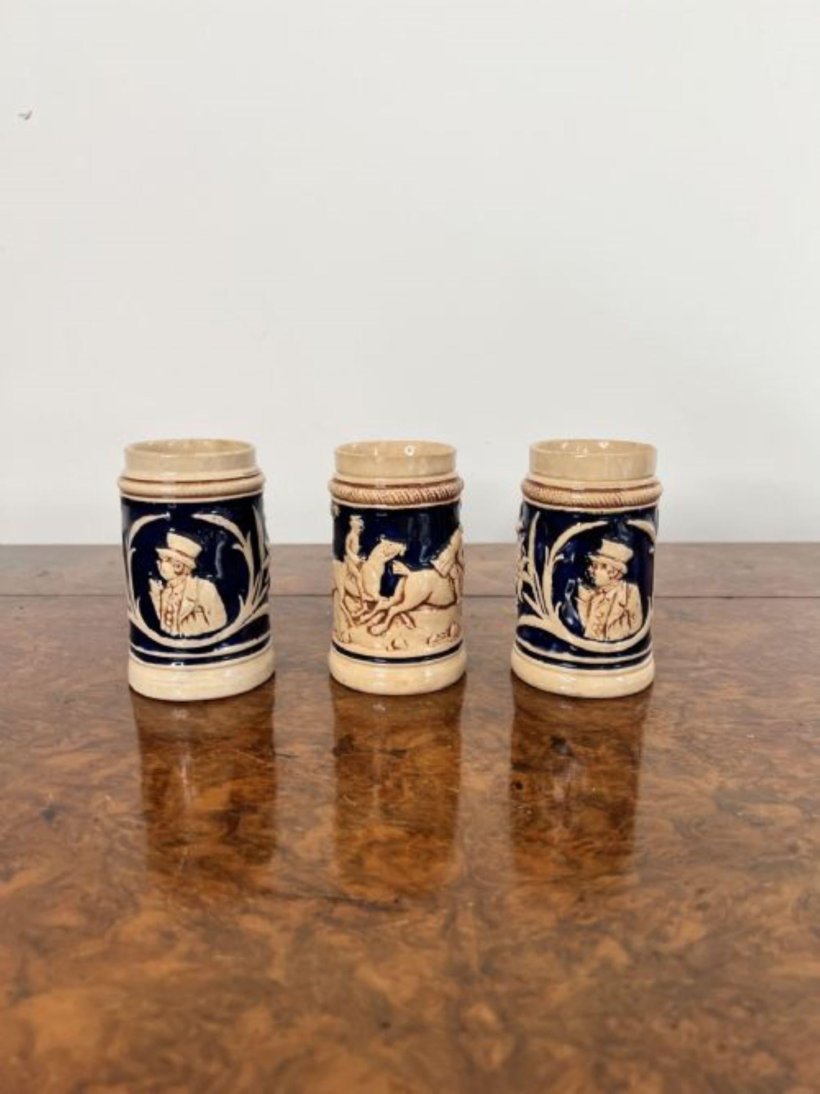 Three quality antique German steins having three quality antique German pottery steins decorated with figures, flowers and horses in brown colours on a royal blue background. 